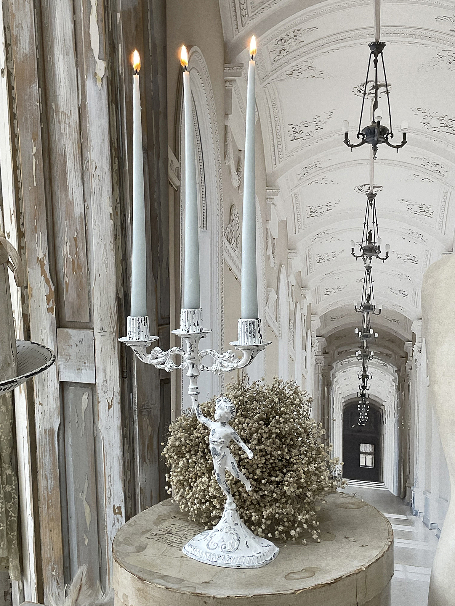 Eleganter Kerzenständer mit drei Kerzen und floraler Dekoration Kreativer Kerzenständer mit drei brennenden Kerzen in einem stilvollen Innenraum