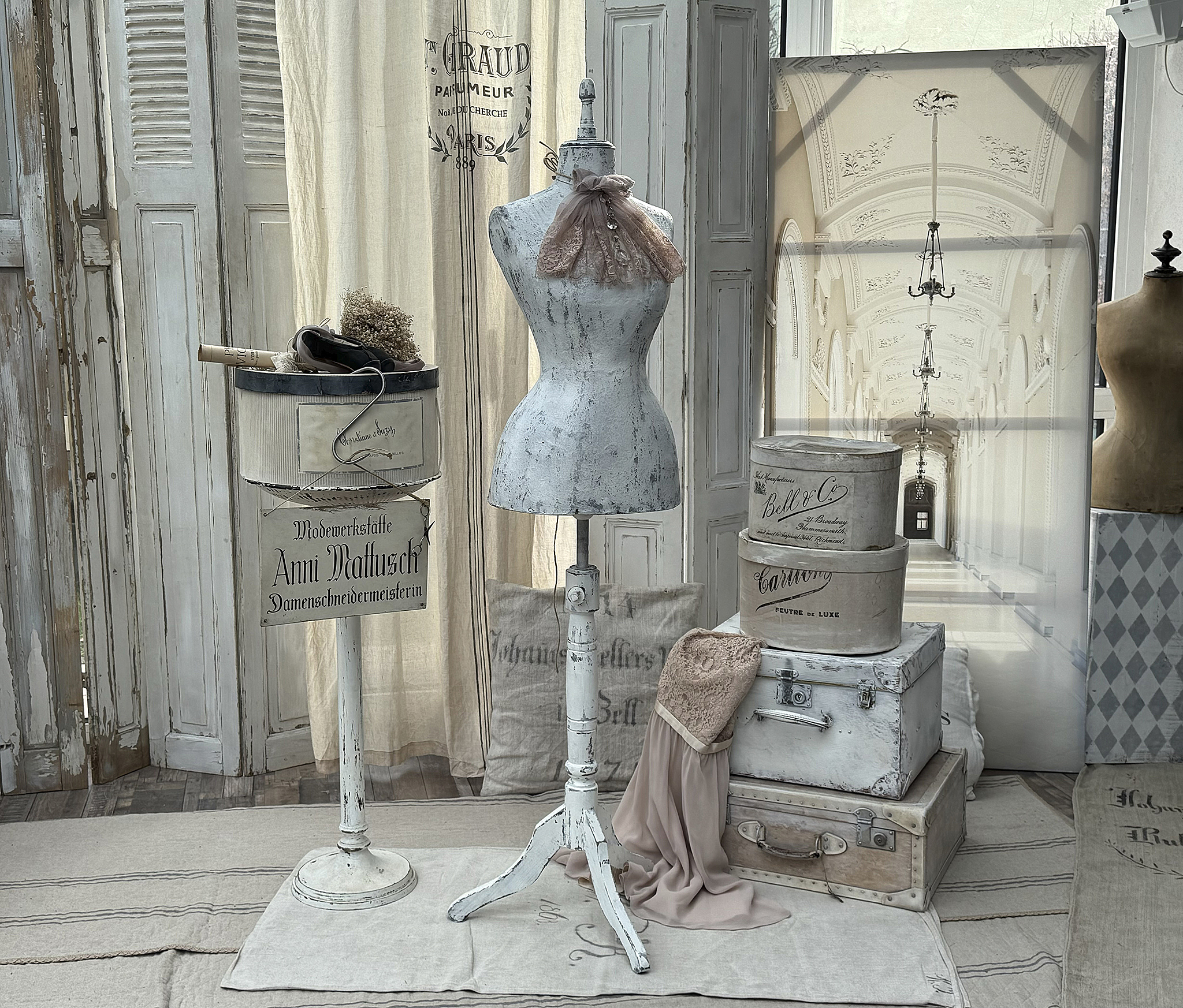 Schaufensterpuppe in einer stilvollen Schneiderwerkstatt mit nostalgischen Accessoires und dekorativen Kisten.