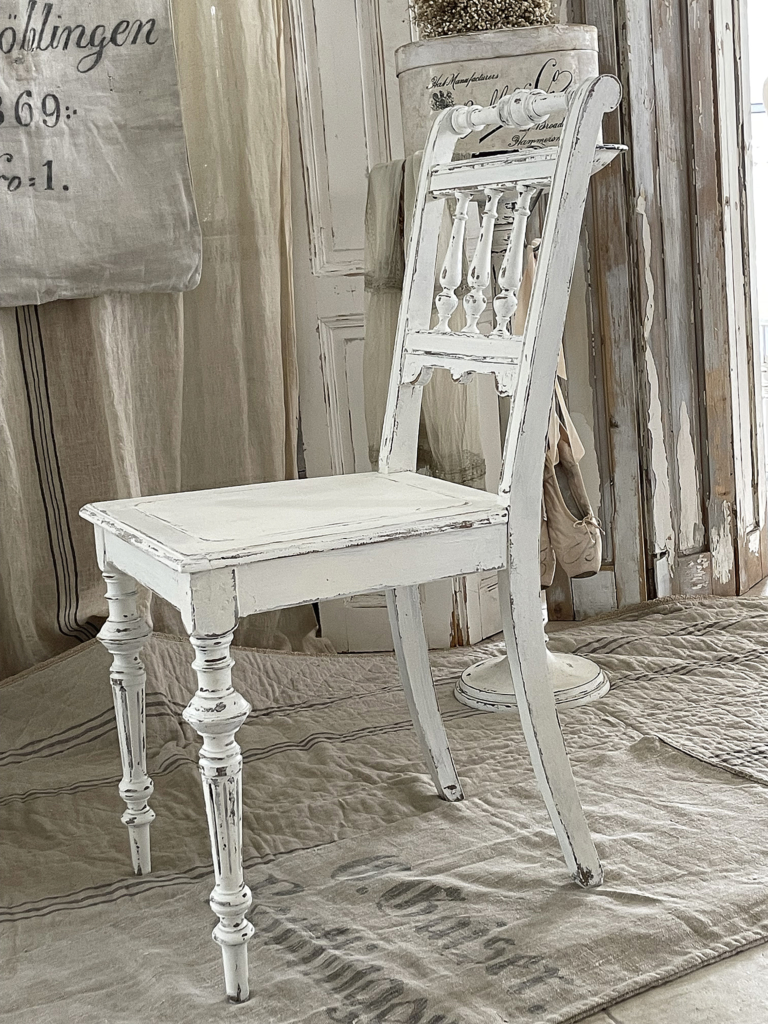 Antiker Holzstuhl in Weiß, ideal für nostalgische Inneneinrichtungen.