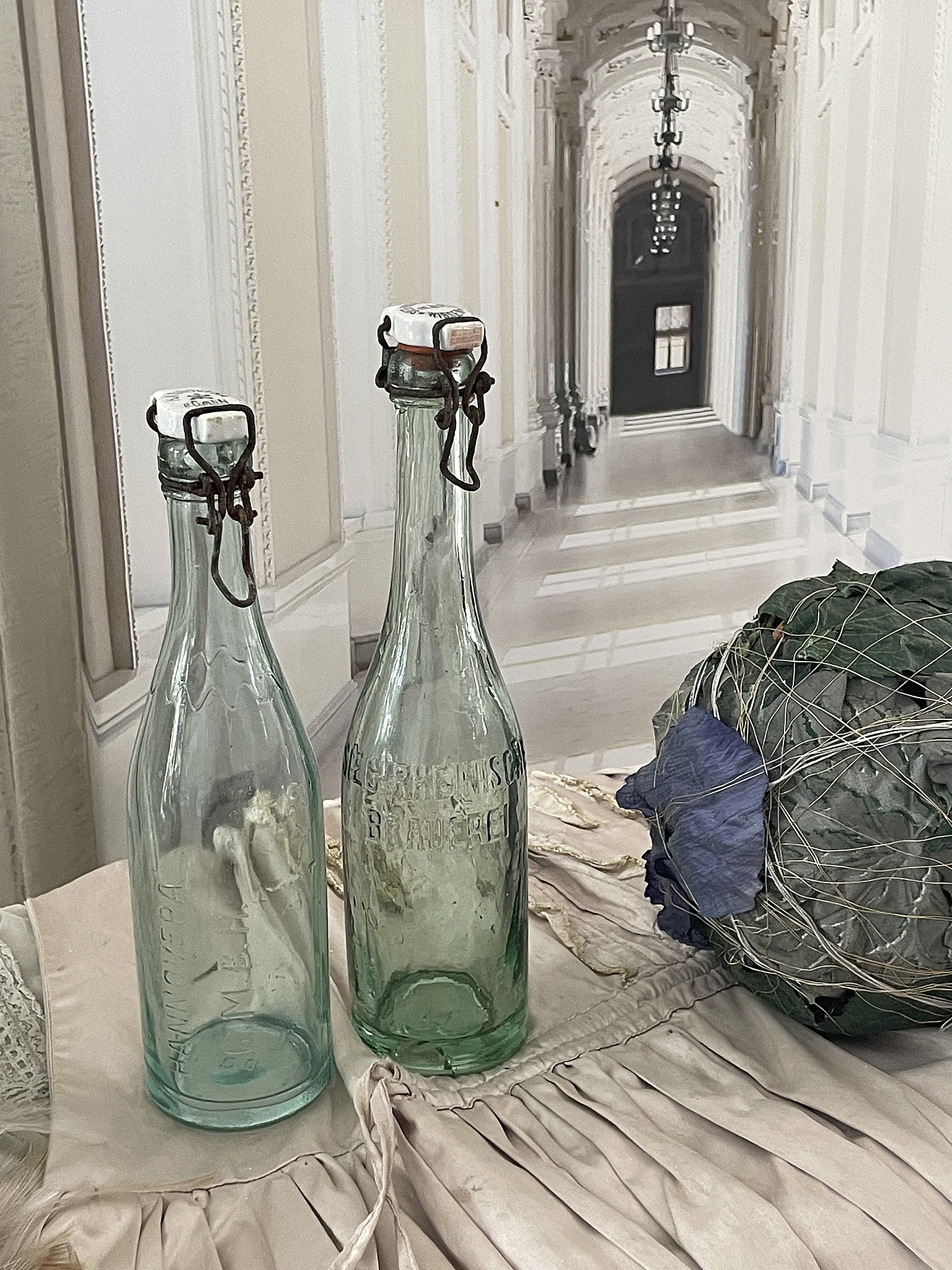 Vintage Flaschen aus Glas auf einem Tisch Zwei alte Glasflaschen neben einer Dekoration aus trockenen Pflanzen auf einem Tisch