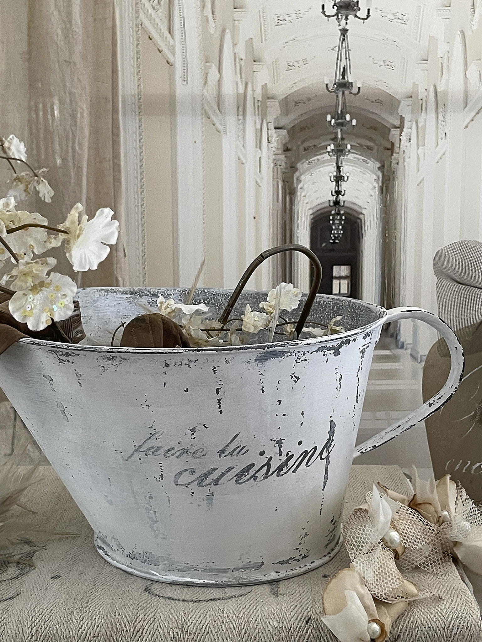 Dekorative Zinkschüssel mit Blumen im Vintage-Stil Eine rustikale Zinkschüssel mit Blumenarrangement, im Hintergrund ein eleganter Korridor