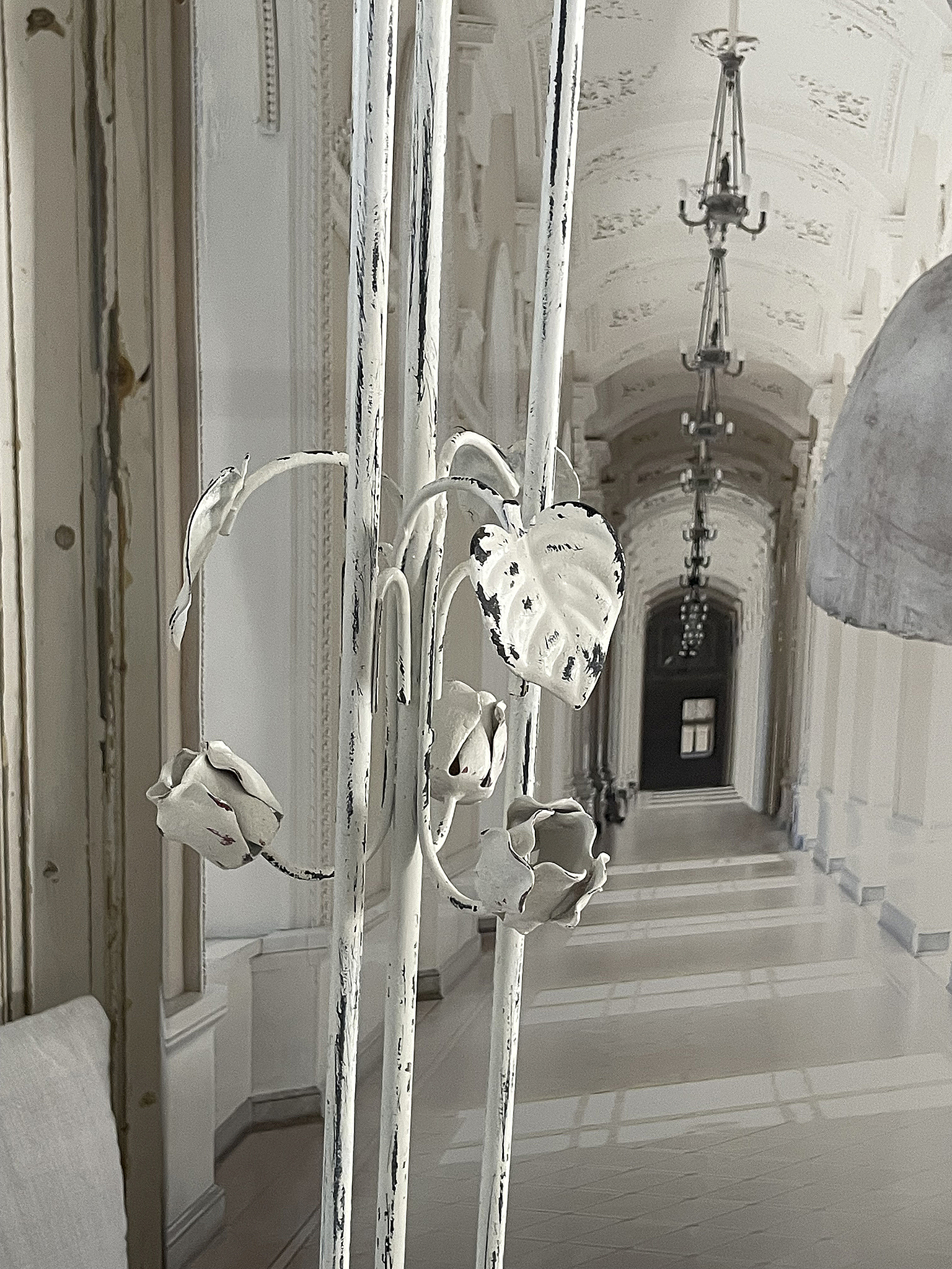 Dekorativer Metallzaun mit kunstvollen Blatt- und Blumenmotiven Ein dekorativer Metallzaun mit weißen Blatt- und Blumenmotiven in einer eleganten Umgebung.