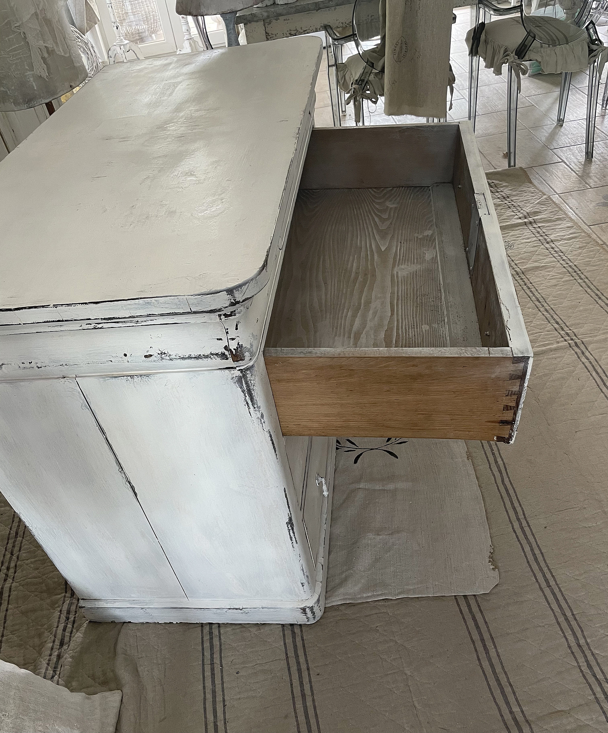 Detailaufnahme einer weißen Kommode mit offener Schublade und holzfarbenem Innenraum.