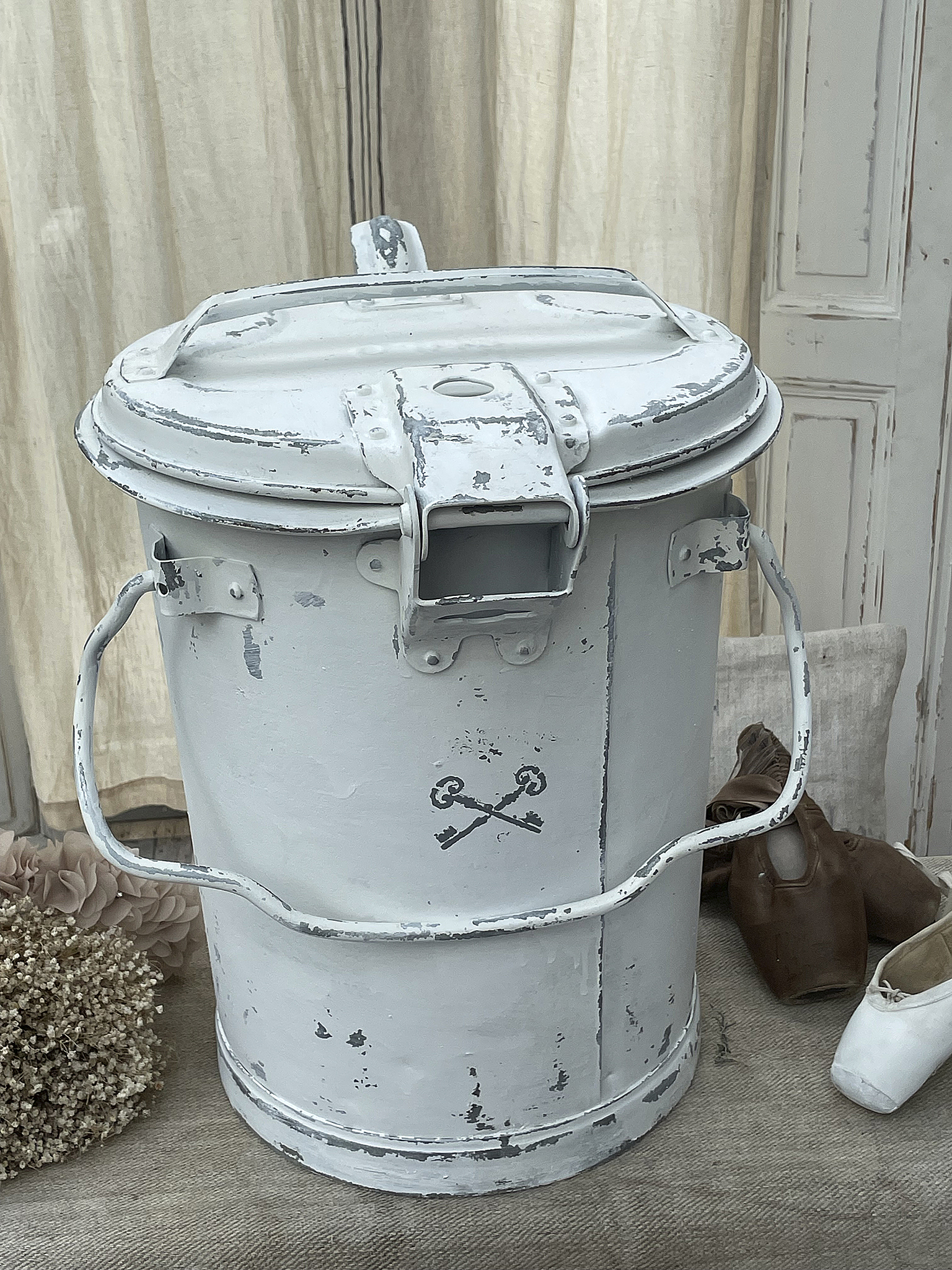 Vintage Eimer mit rostiger Oberfläche und Henkel Weißer Vintage Eimer mit abgeblätterter Farbe und stilisierten Schlüsselsymbolen