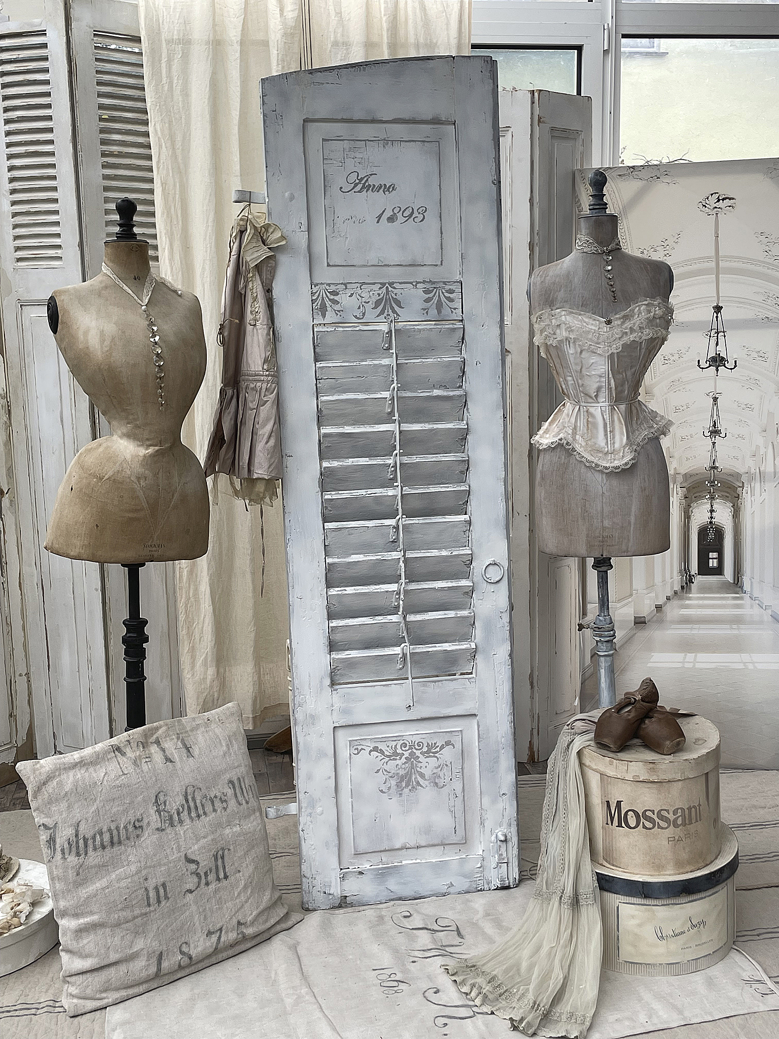 Kreatives Vintage-Arrangement mit Mannequins und Altertümern Dekorative Innenansicht mit Mannequins, einem alten Türscharnier und vintage Accessoires in einem stilvollen Raum.