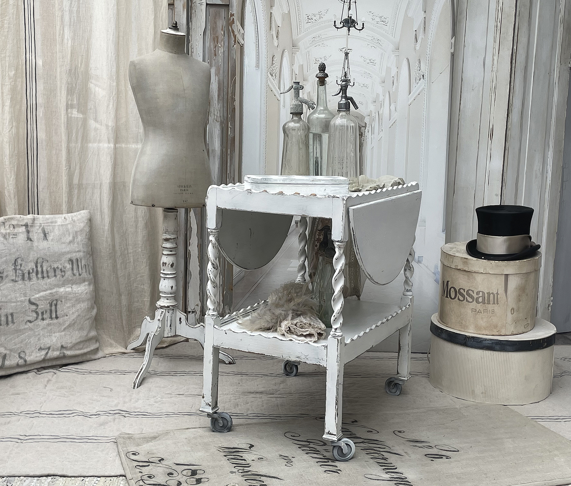 Eleganter Vintage-Wagentisch im Shabby-Chic-Stil Dekorativer Wagentisch mit Glasflaschen und Mannequin in stilvollem Ambiente