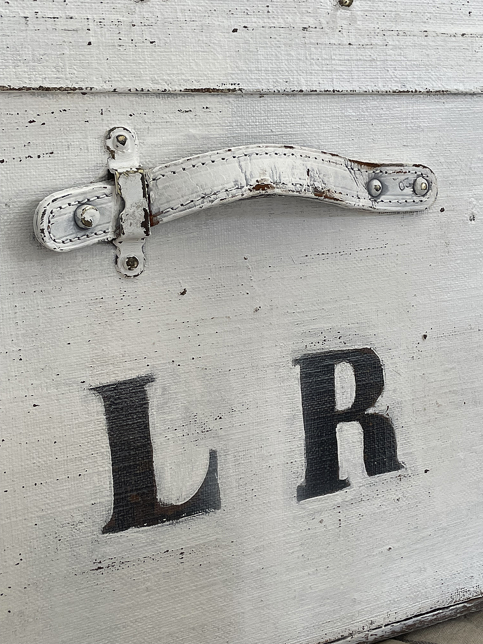 Vintage Kiste mit Ledergriff und Buchstaben L und R Nahaufnahme einer alten Kiste mit einem weißen Ledergriff und den Buchstaben L und R auf der Vorderseite
