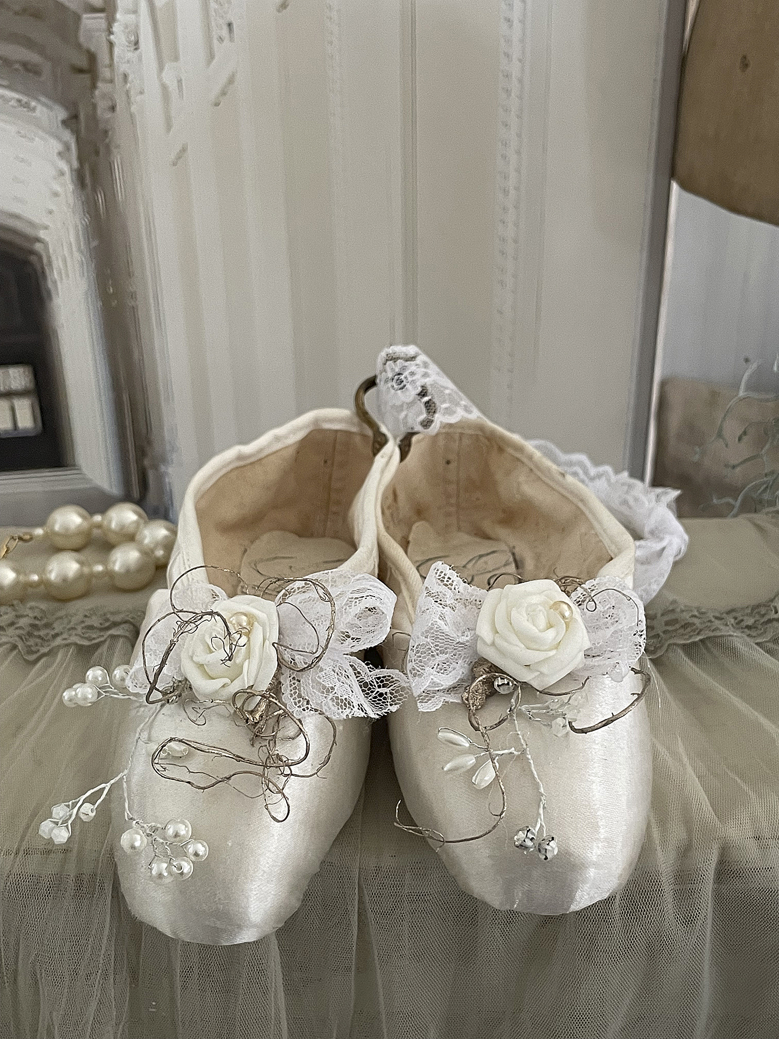 Elegante Ballettschuhe mit Blumendekor und Spitzenverzierung Hübsche Ballettschuhe mit weißen Blumen und zarter Spitze auf einem geschmackvollen Untergrund