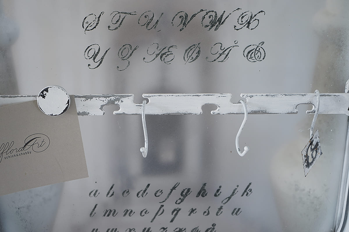 Detailansicht eines antik wirkenden Regals mit Buchstaben und Haken