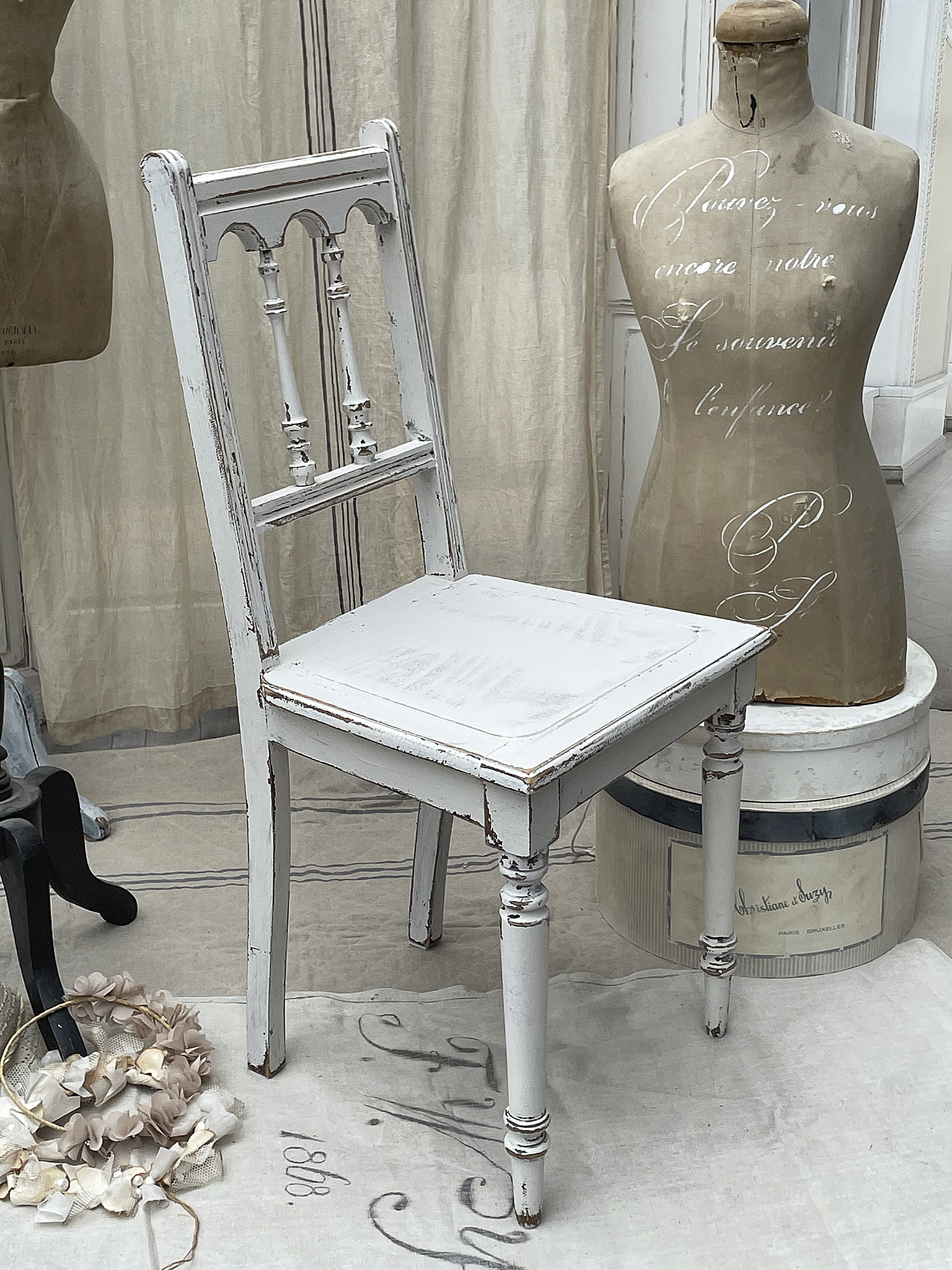 Klassischer Weißer Stuhl im Vintage-Stil Ein eleganter, weißer Vintage-Stuhl mit einem neoklassizistischen Design vor einer dekorativen Kulisse.