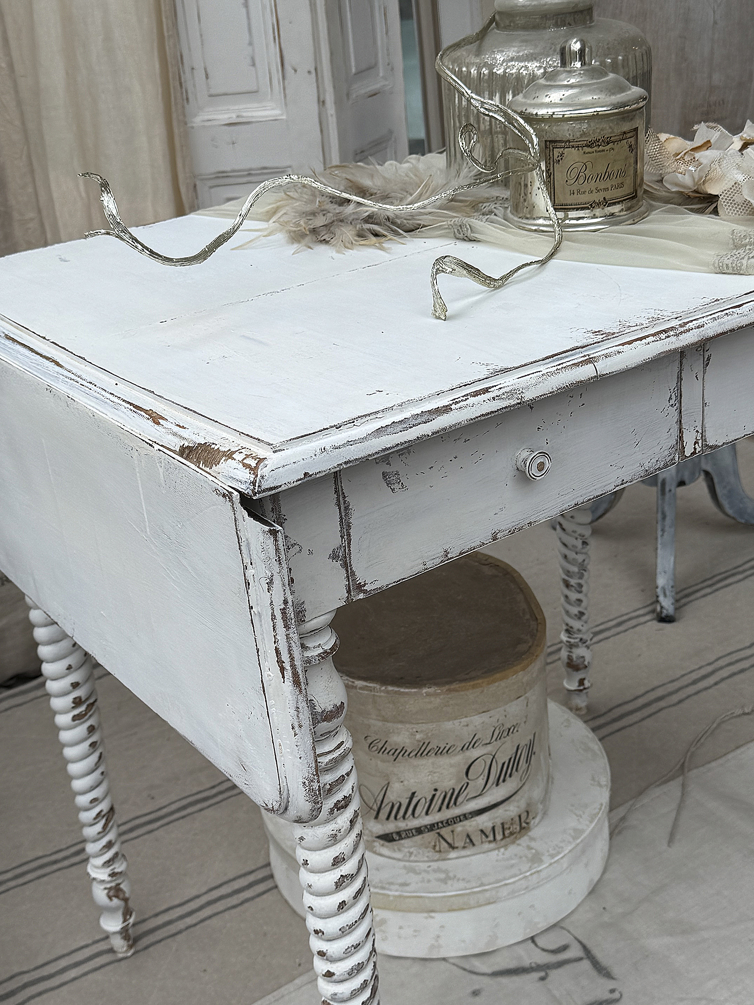 Detailaufnahme eines alten weißen Tisches mit schnörkeligen Beinen und eleganter Dekoration