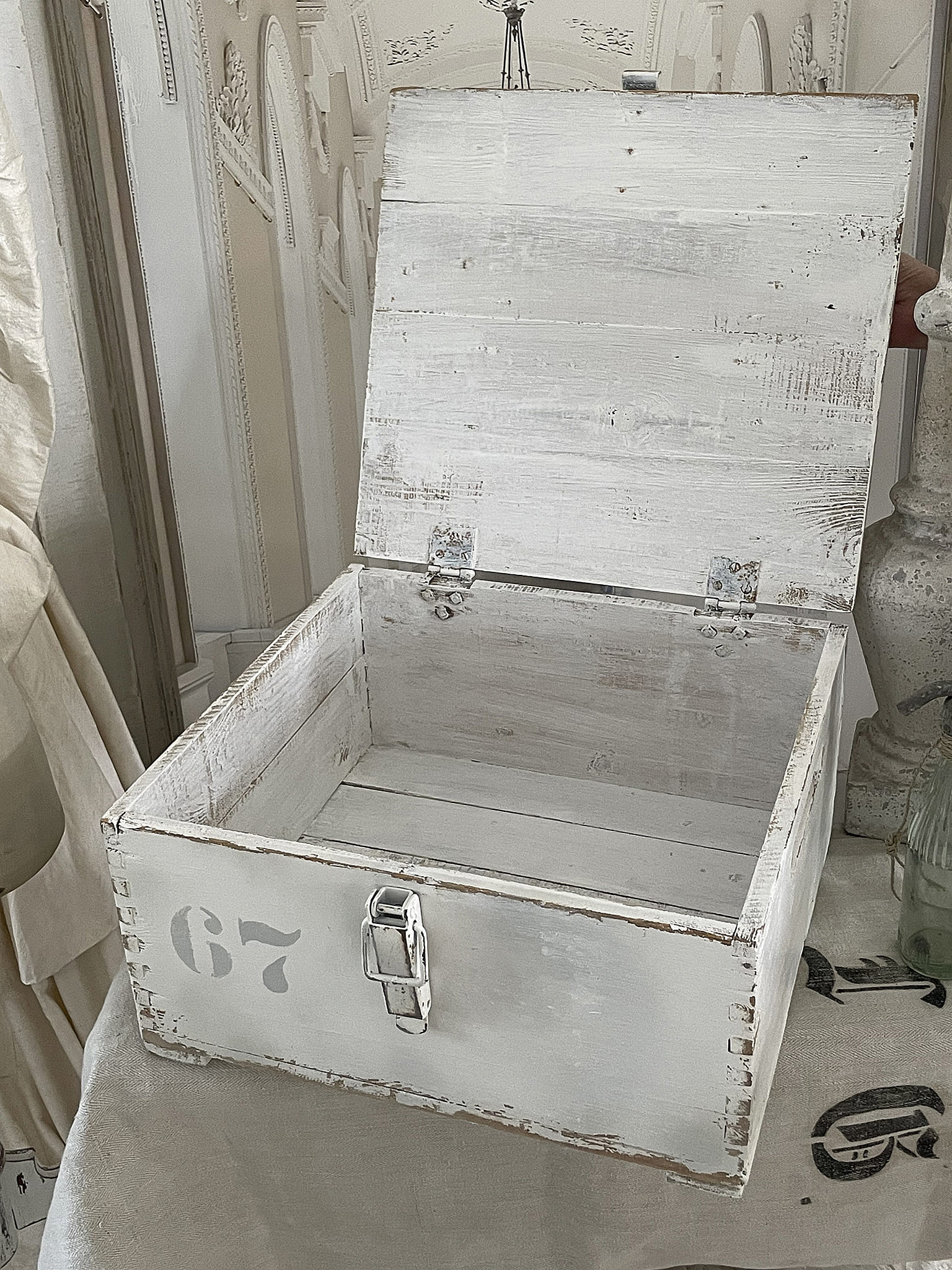 Offene weiße Holzbox mit der Nummer 67, ideal zur Aufbewahrung von Gegenständen.