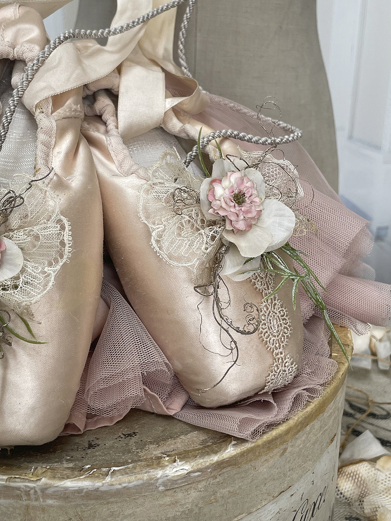 Detailaufnahme von Ballettschuhen mit zarten Blumen und Tüll, dekorativ auf einem Holzbehälter platziert.