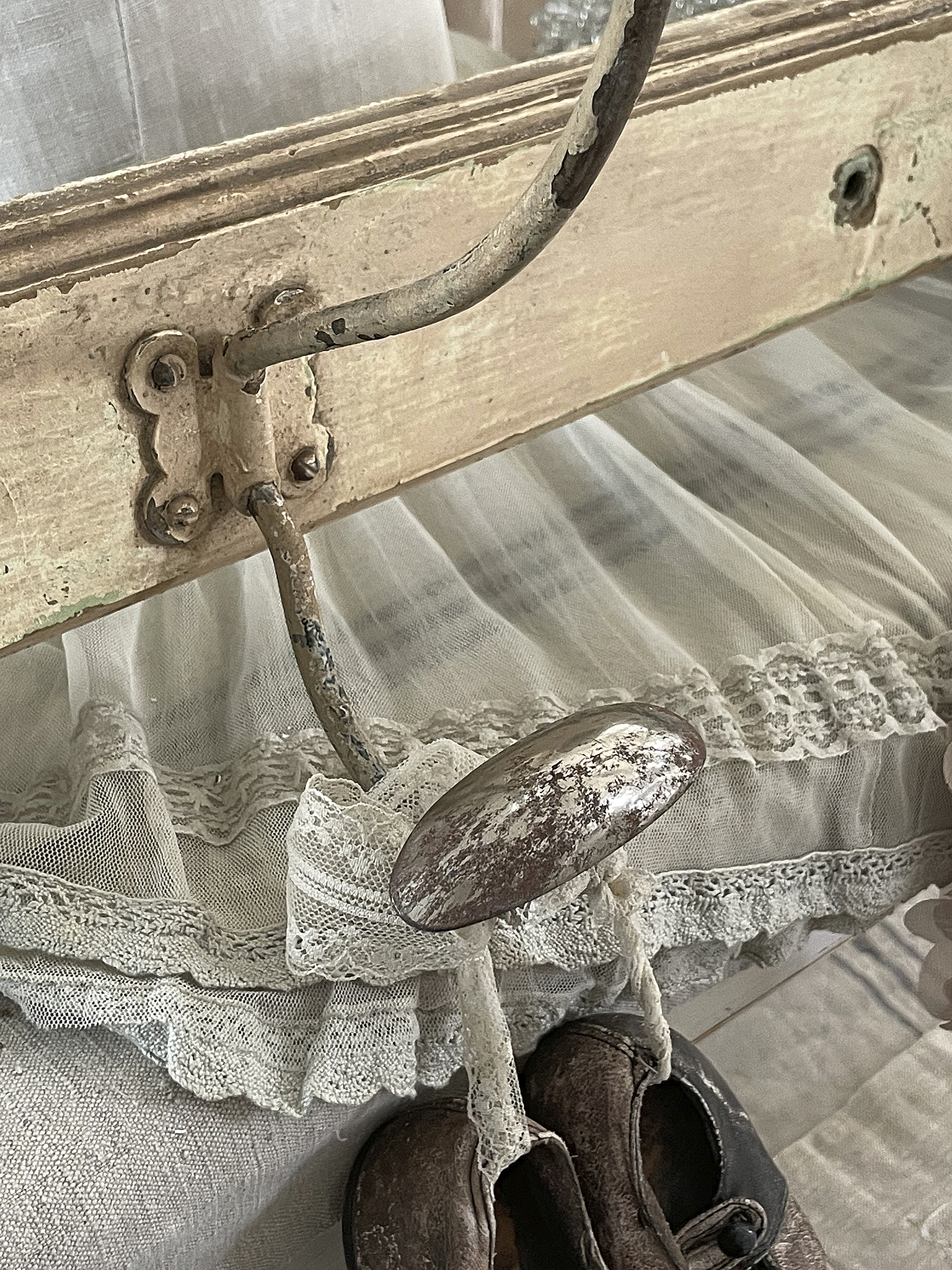 Antiker Kleiderständer mit Zierdetails und alten Schuhen Detailaufnahme eines antiken Kleiderständers mit einem kreativen Haken und Verzierung sowie einem Paar alter Schuhe.