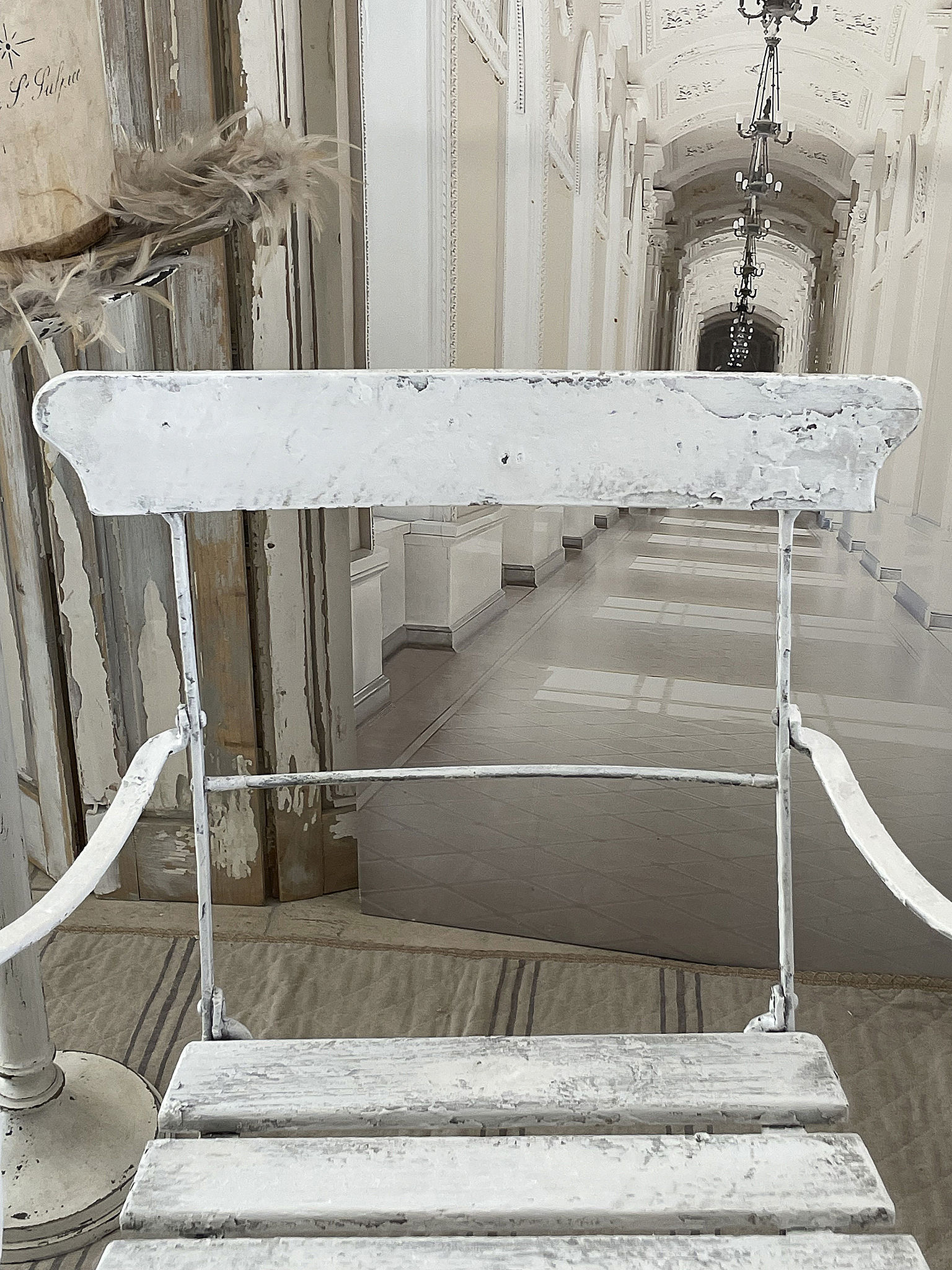 Vintage klappbarer Metallstuhl in Weiß mit nostalgischem Flair Weißer klappbarer Metallstuhl vor einer eleganten, klassischen Innenarchitektur