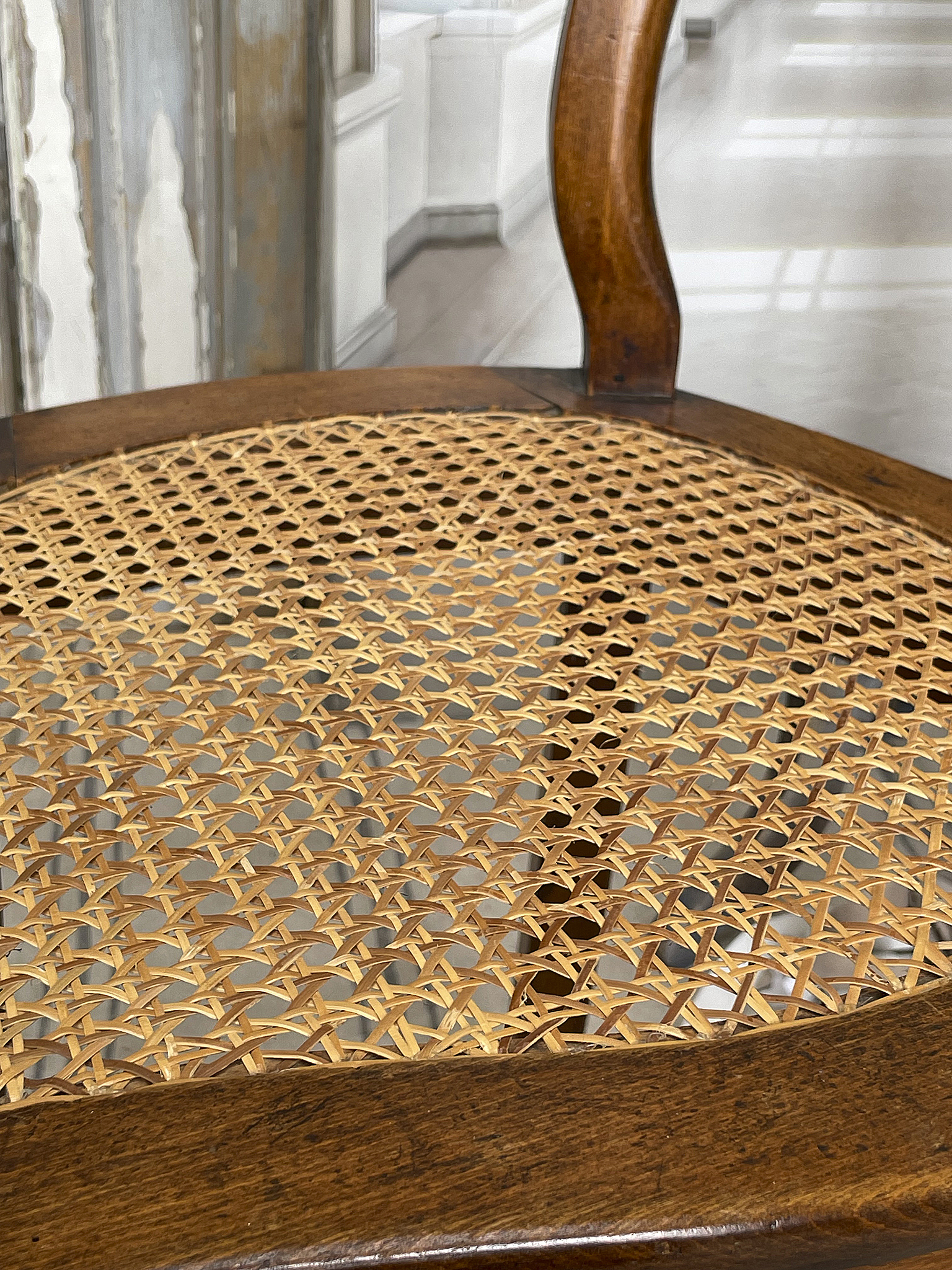 Bequemer Stuhl mit geflochtenem Sitz aus Rattan Naheaufnahme des geflochtenen Sitzes eines Stuhls aus Holz mit Rattan