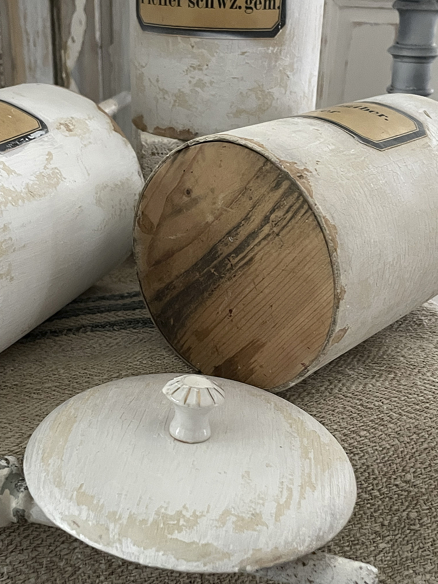 Dekorative Holzbehälter mit weißen Lackierungen und Holzdetails Detailaufnahme von alten Holzbehältern mit abblätterndem weißen Lack und Holzunterseite