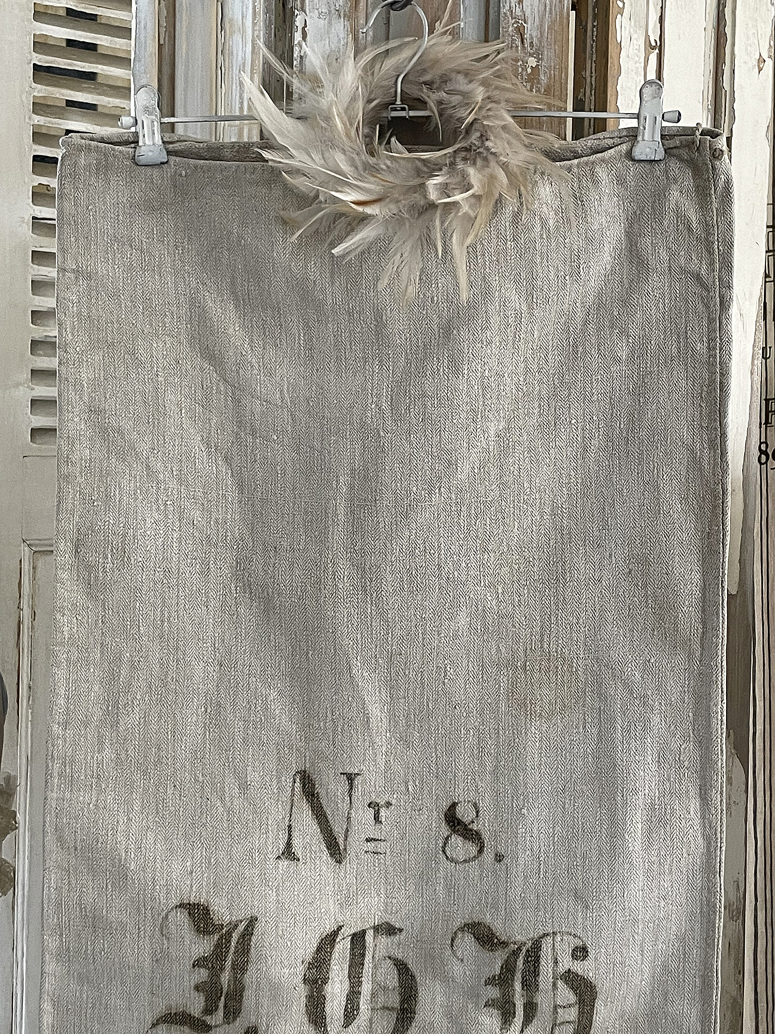 Wandbild aus Stoff in Beige mit der Aufschrift Nr. 8 und Federkranz