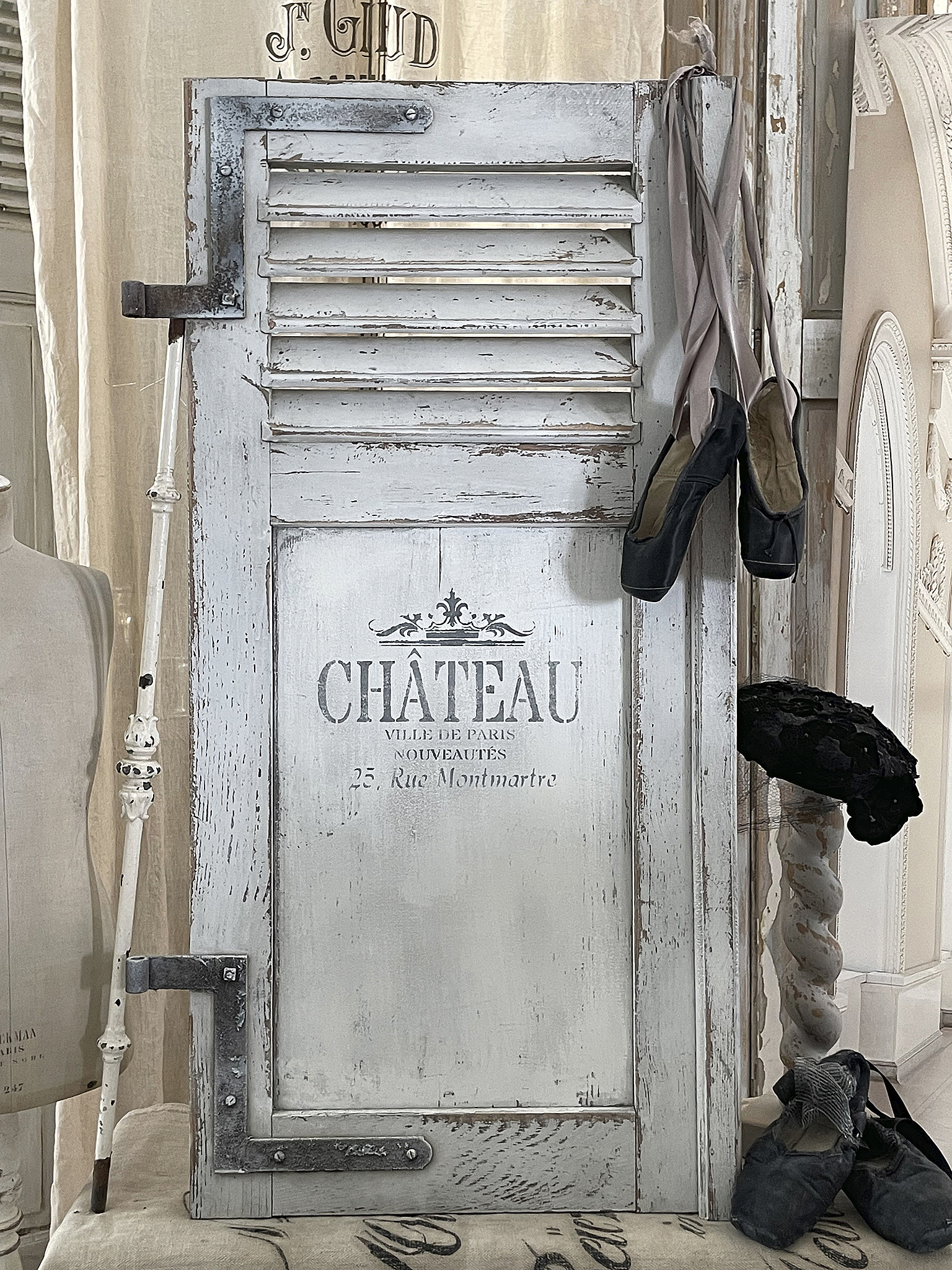 Vintage Tür mit Ballettschuhen und Paris-Motiv Detailaufnahme einer weißen Vintage-Tür mit Ballettschuhen, darauf steht 'CHÂTEAU, 25 Rue Montmartre, Paris'.
