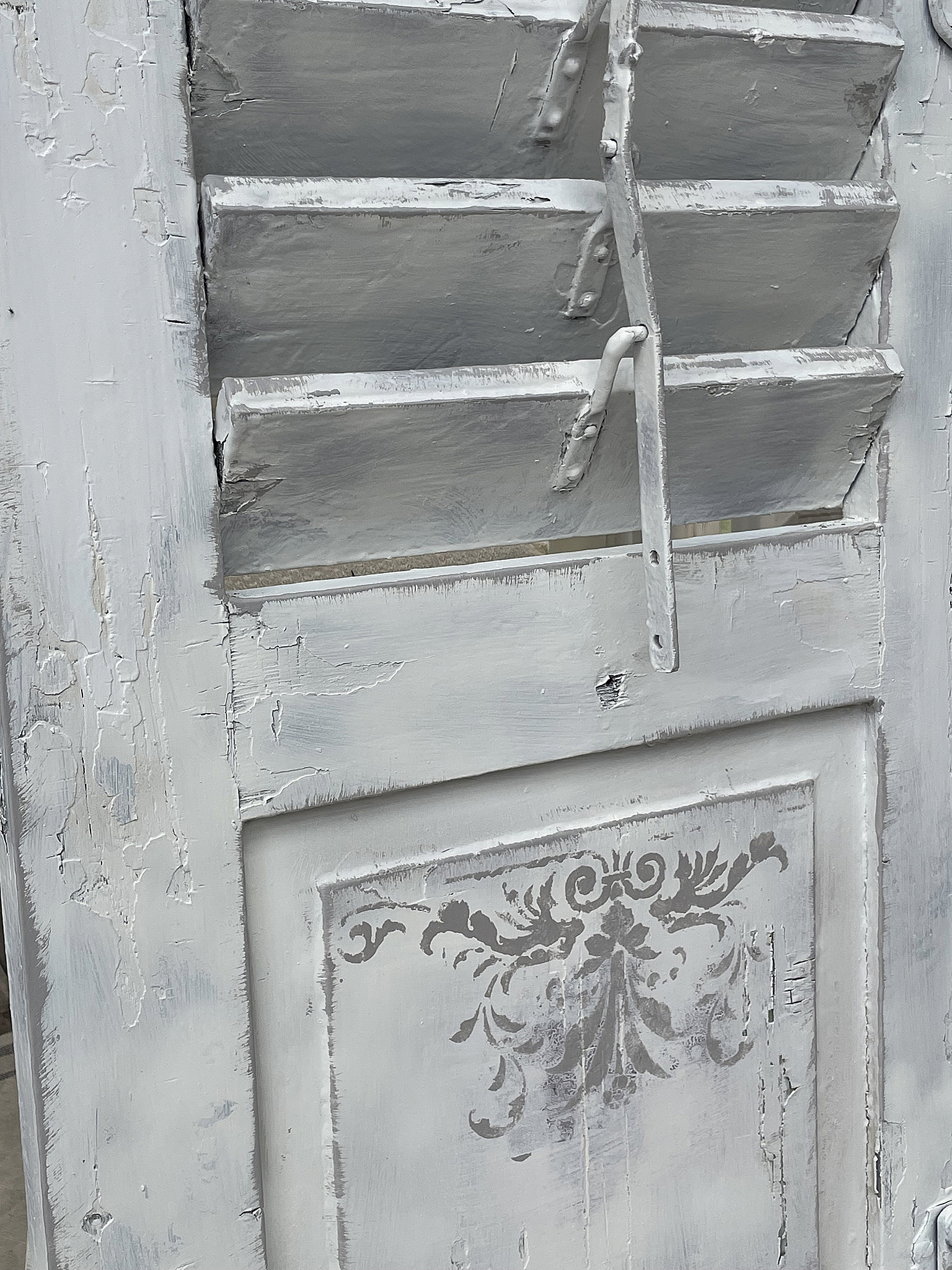 Antiker, shabby-chic Fensterladen in zartem Grau mit dekorativem Muster Shabby-chic Fensterladen in Grau mit stilvollem Ornament