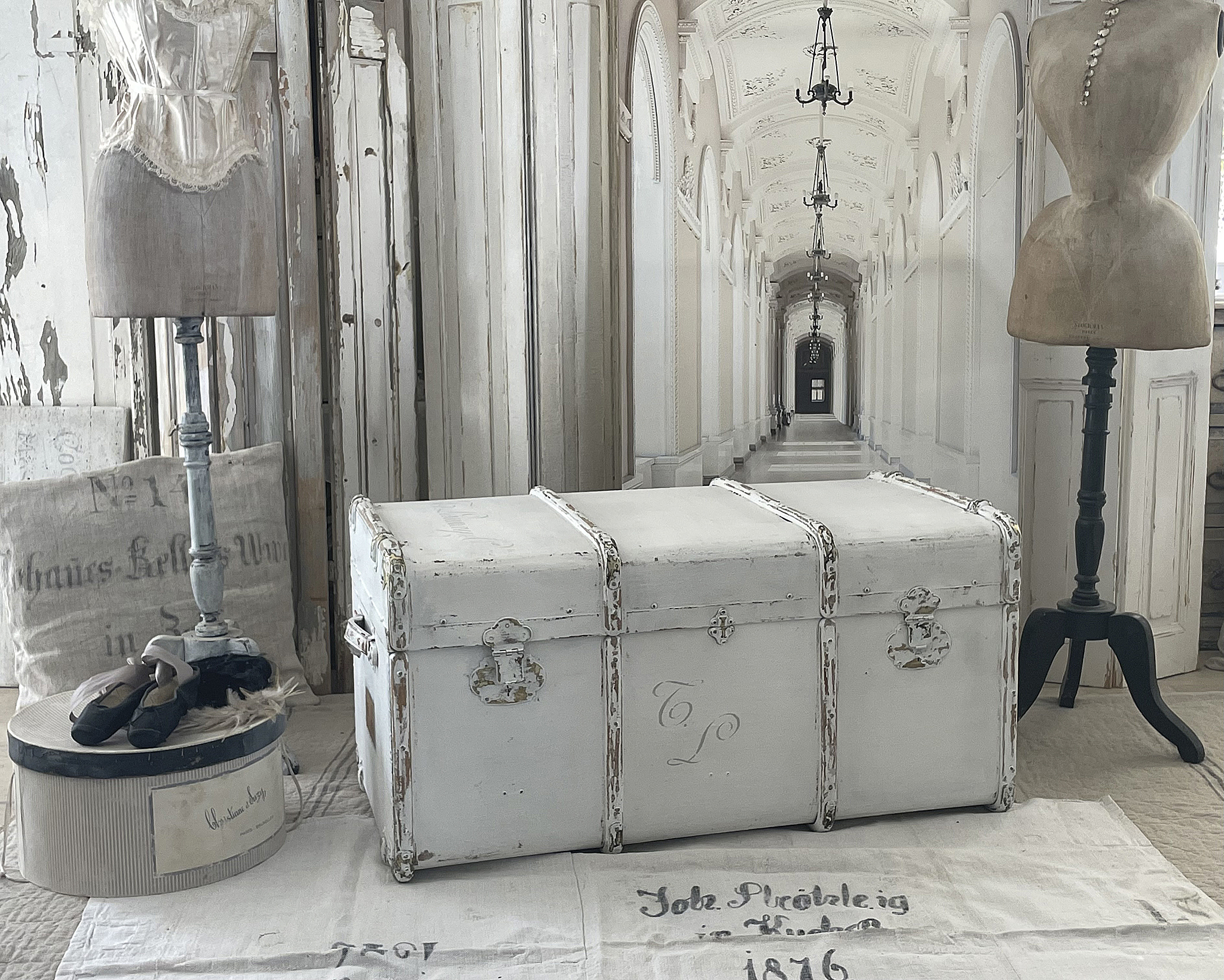 Weiße antike Truhe mit silbernen Beschlägen und vintage Details, eingerahmt von stilvollen Dekorationsgegenständen.