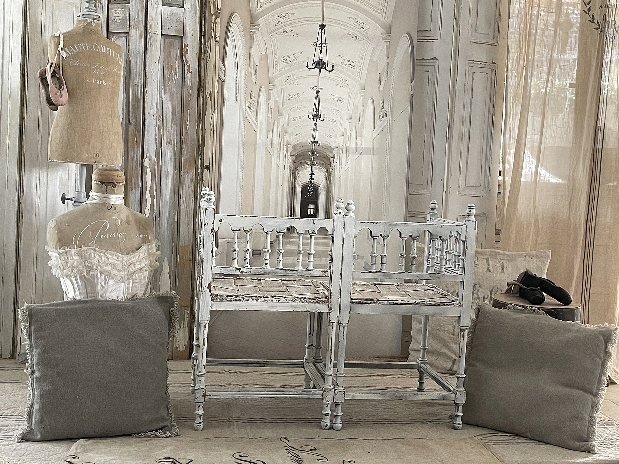 Vintage Einrichtungsstil mit Mannequins und einem weißen Holzgestell Stimmungsvolles Interieur mit vintage Mannequins, einem weißen Holzgestell und dekorativen Kissen.