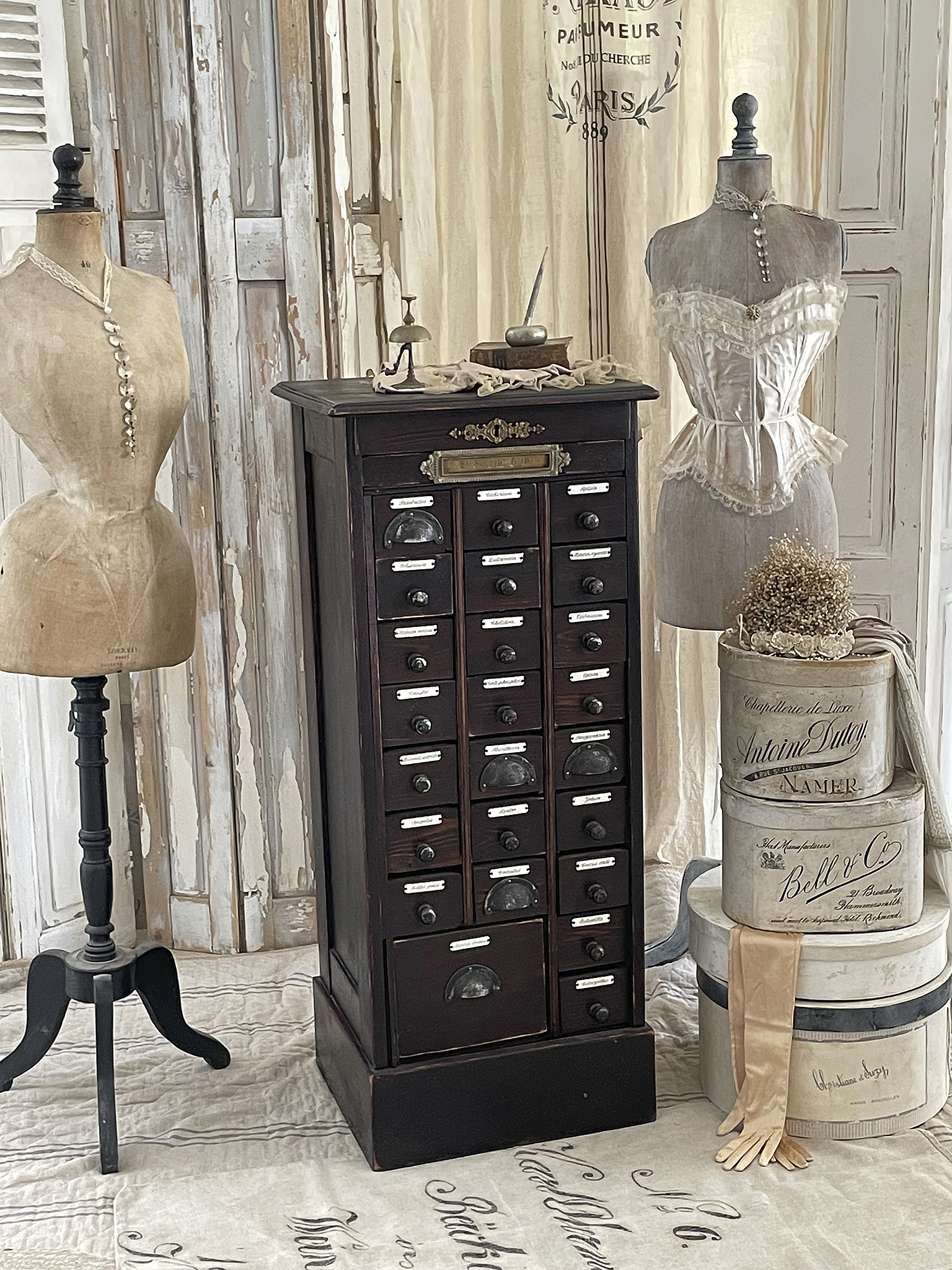 Dekorativer Vintage-Schrank mit Schubladen, umgeben von Mannequins und stilvollen Accessoires