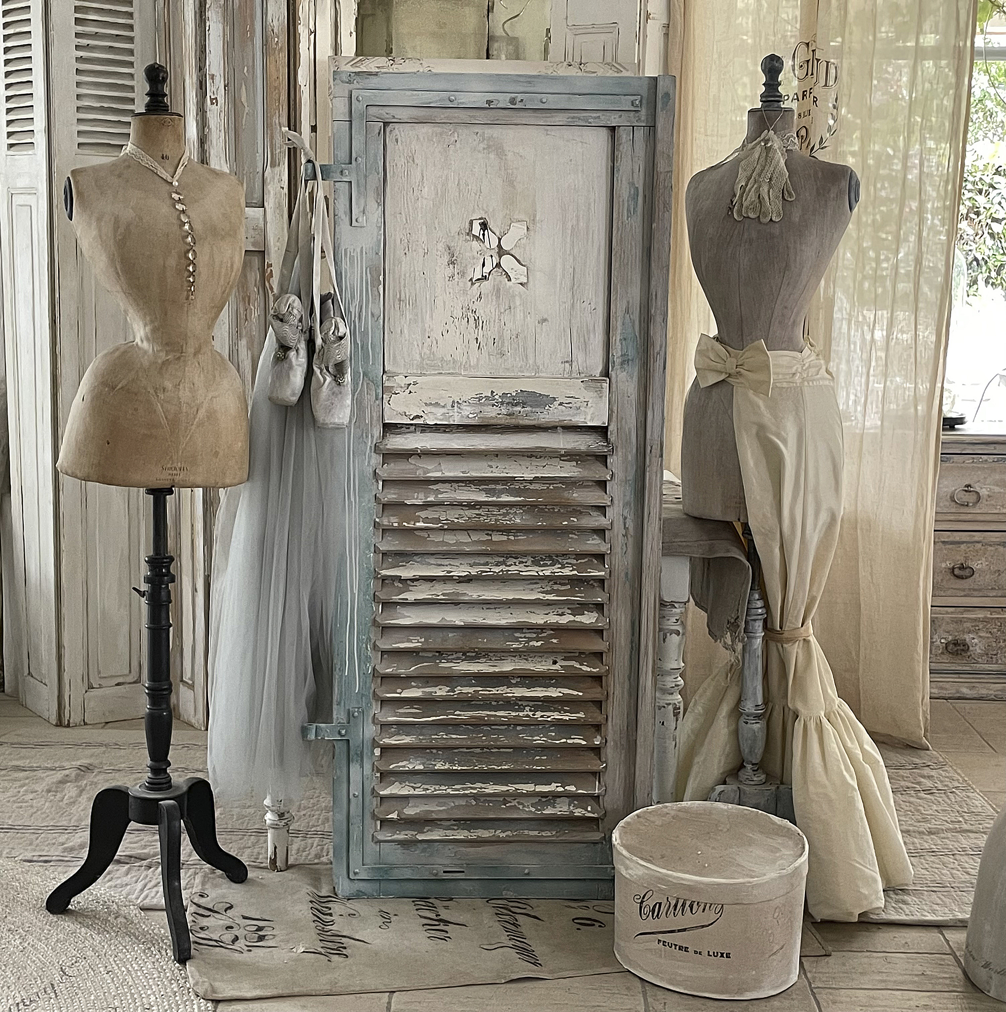 Vintage Nähatelier mit Mannequins und alten Möbeln Ein stilvolles Nähatelier mit zwei Mannequins, einer Holzjalousie und nostalgischen Accessoires.