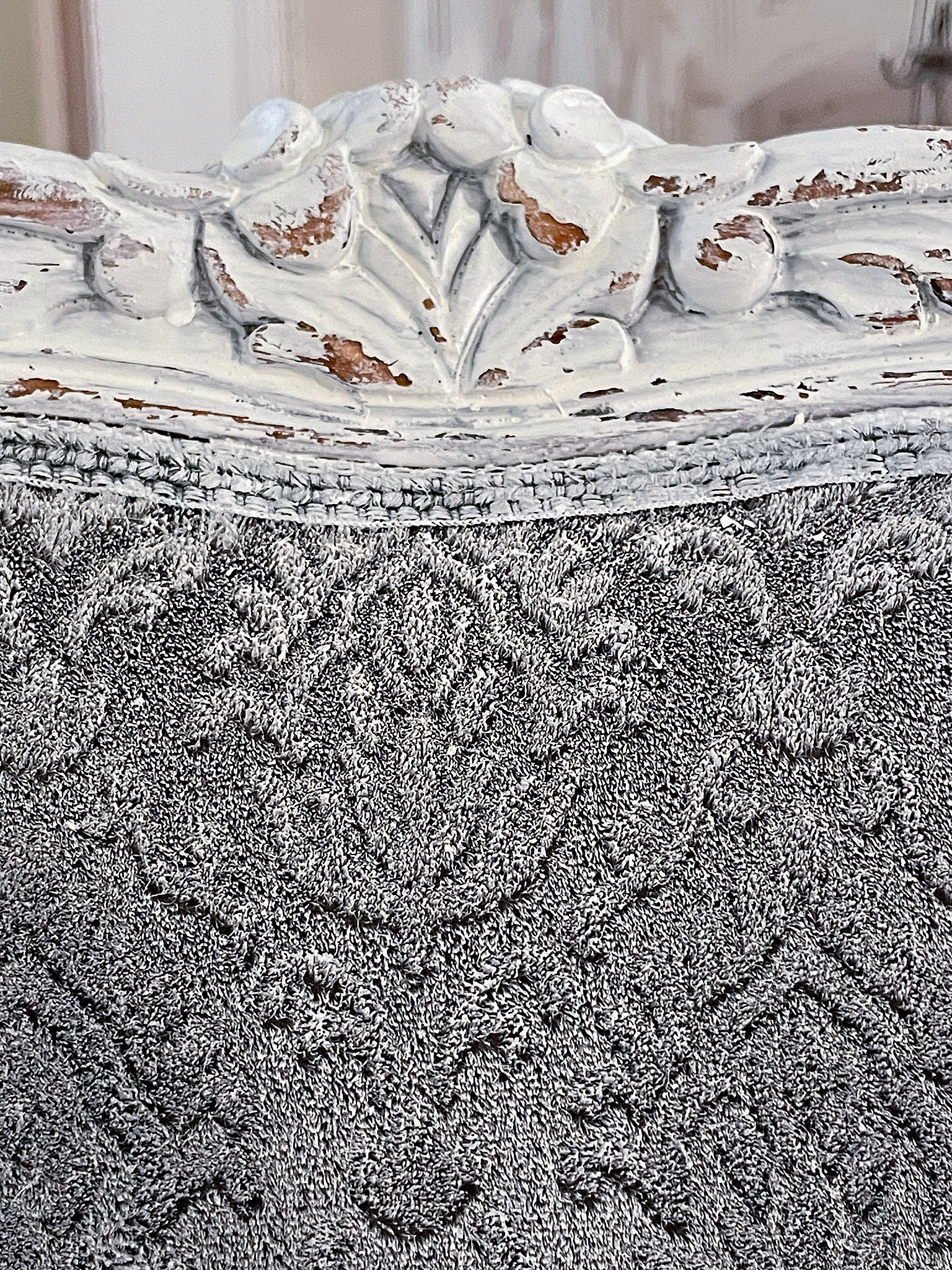Elegante, vintage dekorierte Rückenlehne mit feinem Stoff Detailansicht einer kunstvoll verzierten Rückenlehne mit grauem, texturiertem Stoff