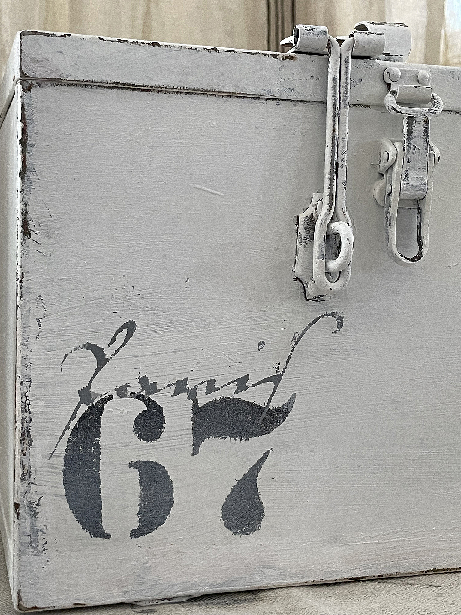 Vintage Aufbewahrungsbox mit nummerierter Dekoration Detailansicht einer antiken Aufbewahrungsbox in Weiß mit der Nummer 67.