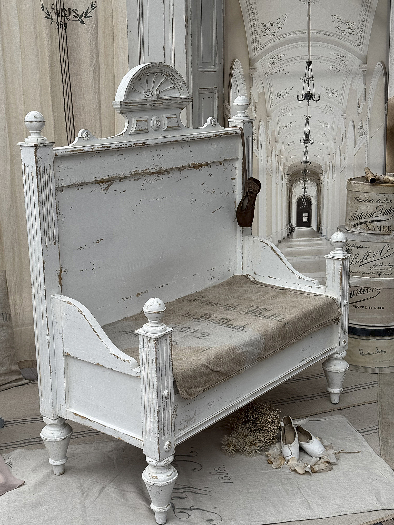 Antikes weißes Holzsofa im Landhausstil mit Kissen Elegantes antikes Holzsofa mit einem Kissen, dekoriert mit Schuhen und Trockenblumen.