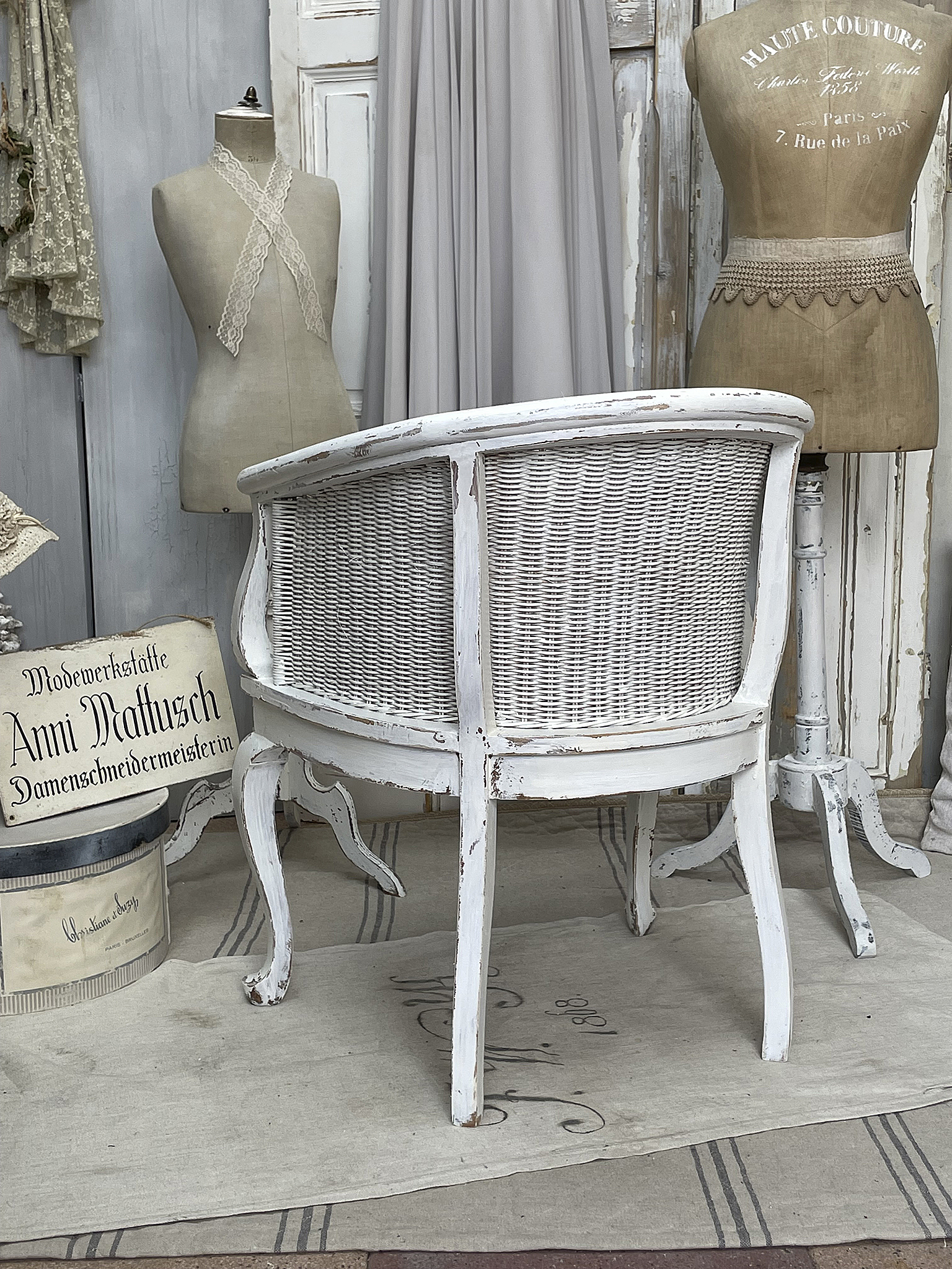 Runder, vintage Stuhl mit geflochtener Rückenlehne in weißem Finish Eleganter, vintage Stuhl mit geflochtener Rückenlehne und abgenutztem weißen Anstrich, dekoriert im nostalgischen Raum