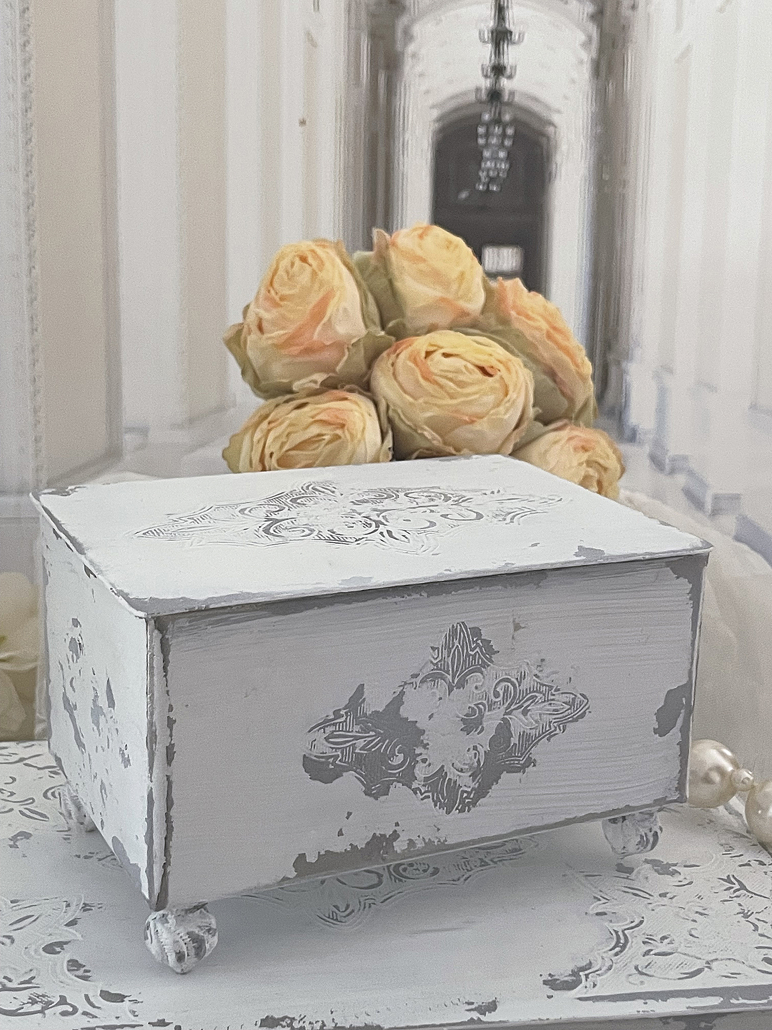 Vintage Aufbewahrungsbox mit zartem Design und Blumenarrangement im Hintergrund