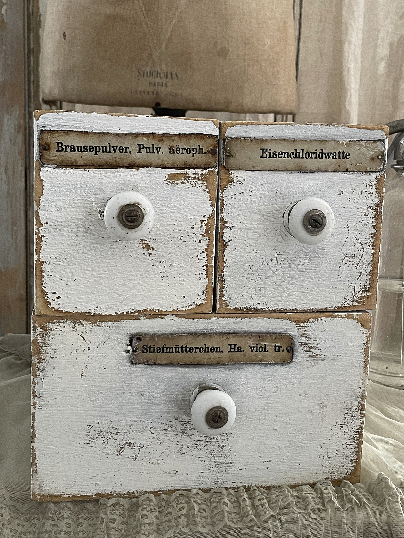 Detailaufnahme eines antiken Apothekenschranks mit Schubladenbeschriftungen: Brausepulver, Eisenchloridwatte und Stiefmütterchen.