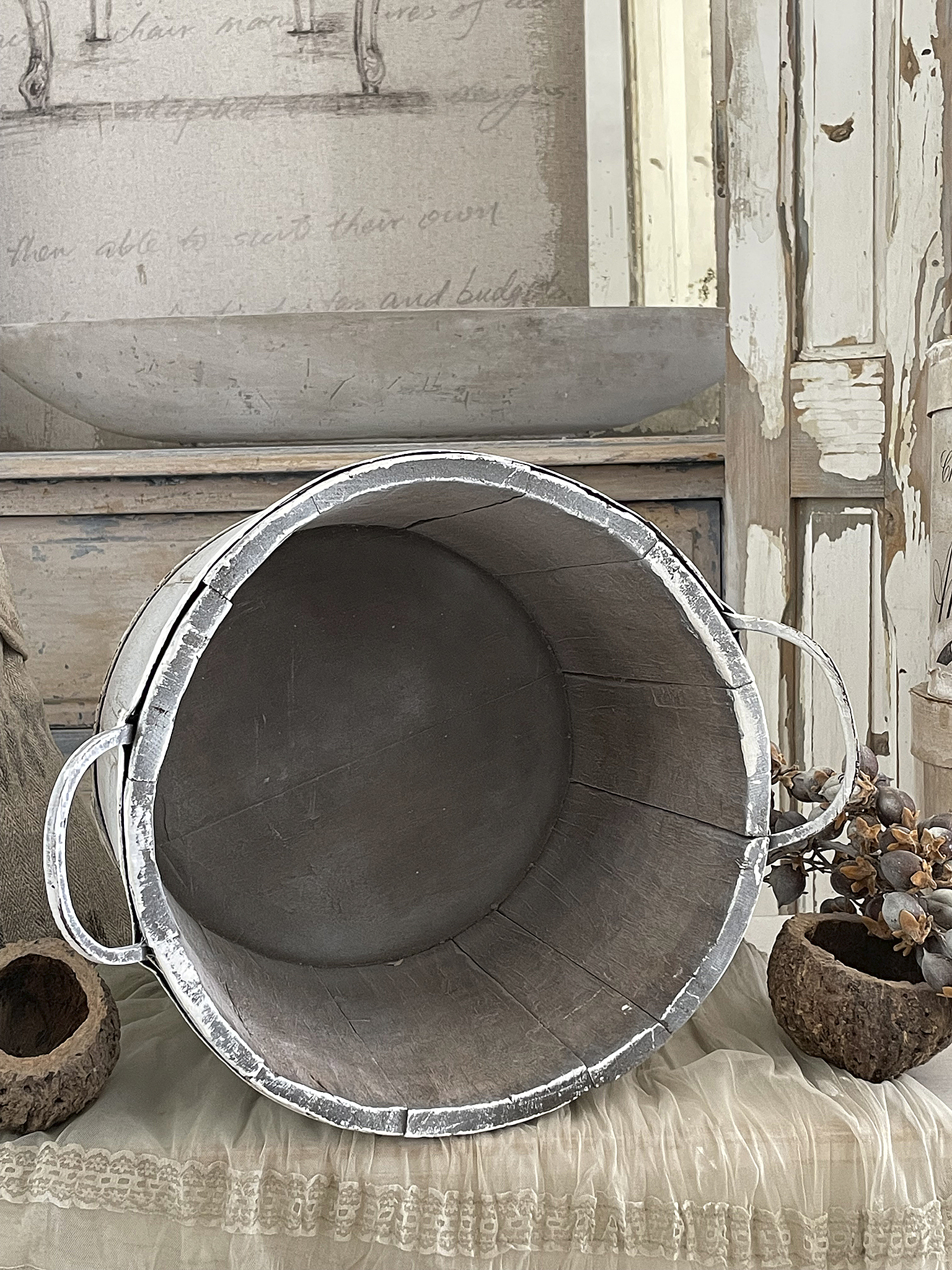 Runde vintage Metallschüssel mit Holzuntergrund Innensicht einer runden Metallschüssel auf einem weichen Stoff, umgeben von Dekorationsobjekten