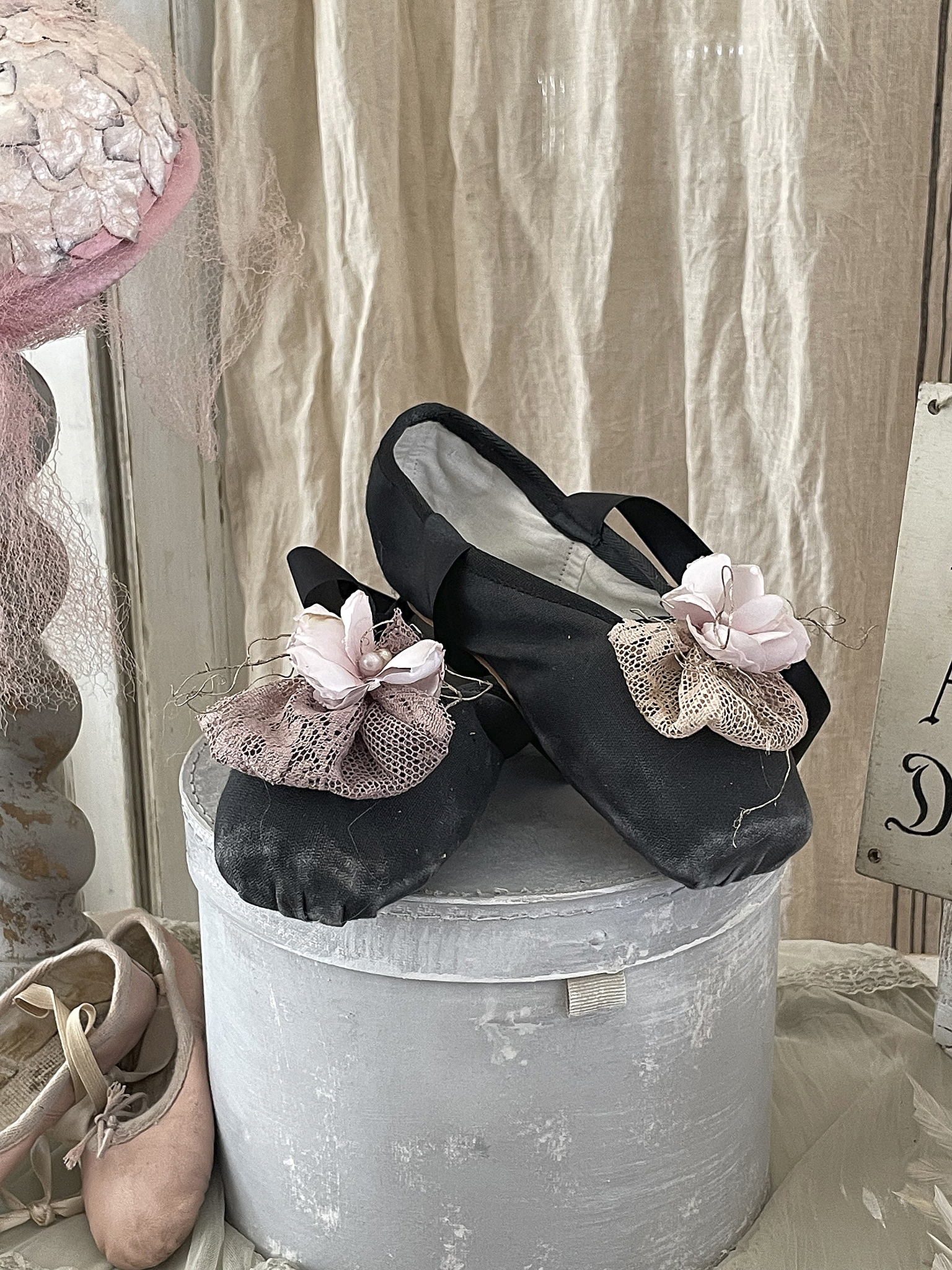 Wunderschöne Ballettschuhe mit floralen Details Elegante schwarze Ballettschuhe mit rosa Blumenapplikationen auf einem grauen Hocker