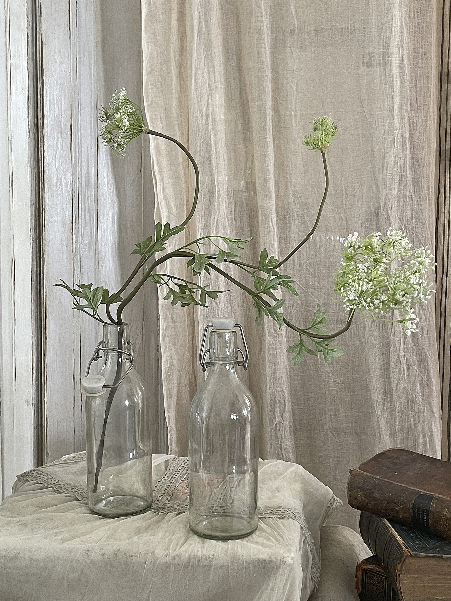 Vase mit Blumen in Glasflaschen auf einem Tisch mit Vintage-Büchern