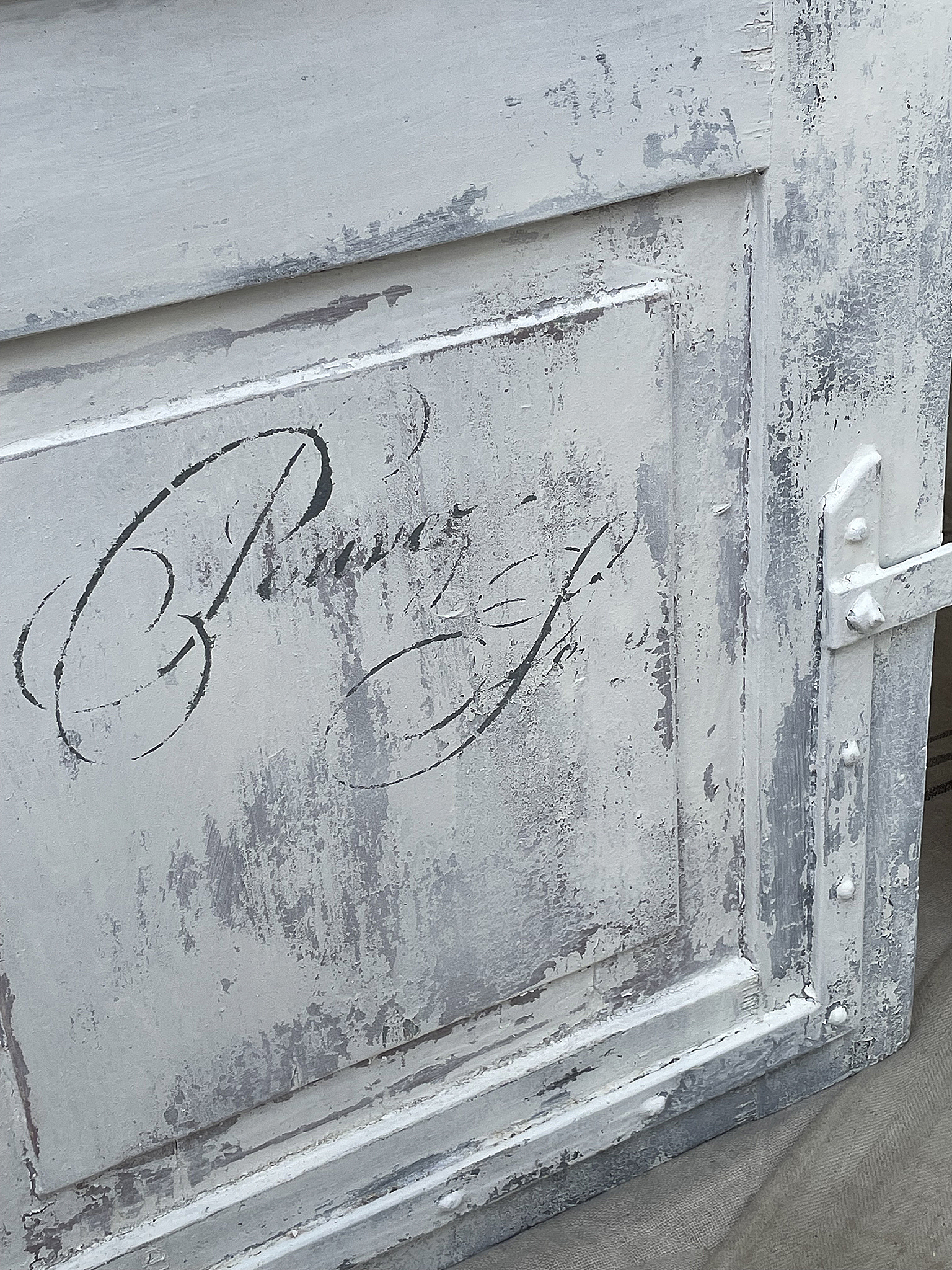 Antike Holzkiste mit verwaschener weißen Farbe Detailansicht einer antiken Holzkiste in weißem Finish mit elegantem Schriftzug.