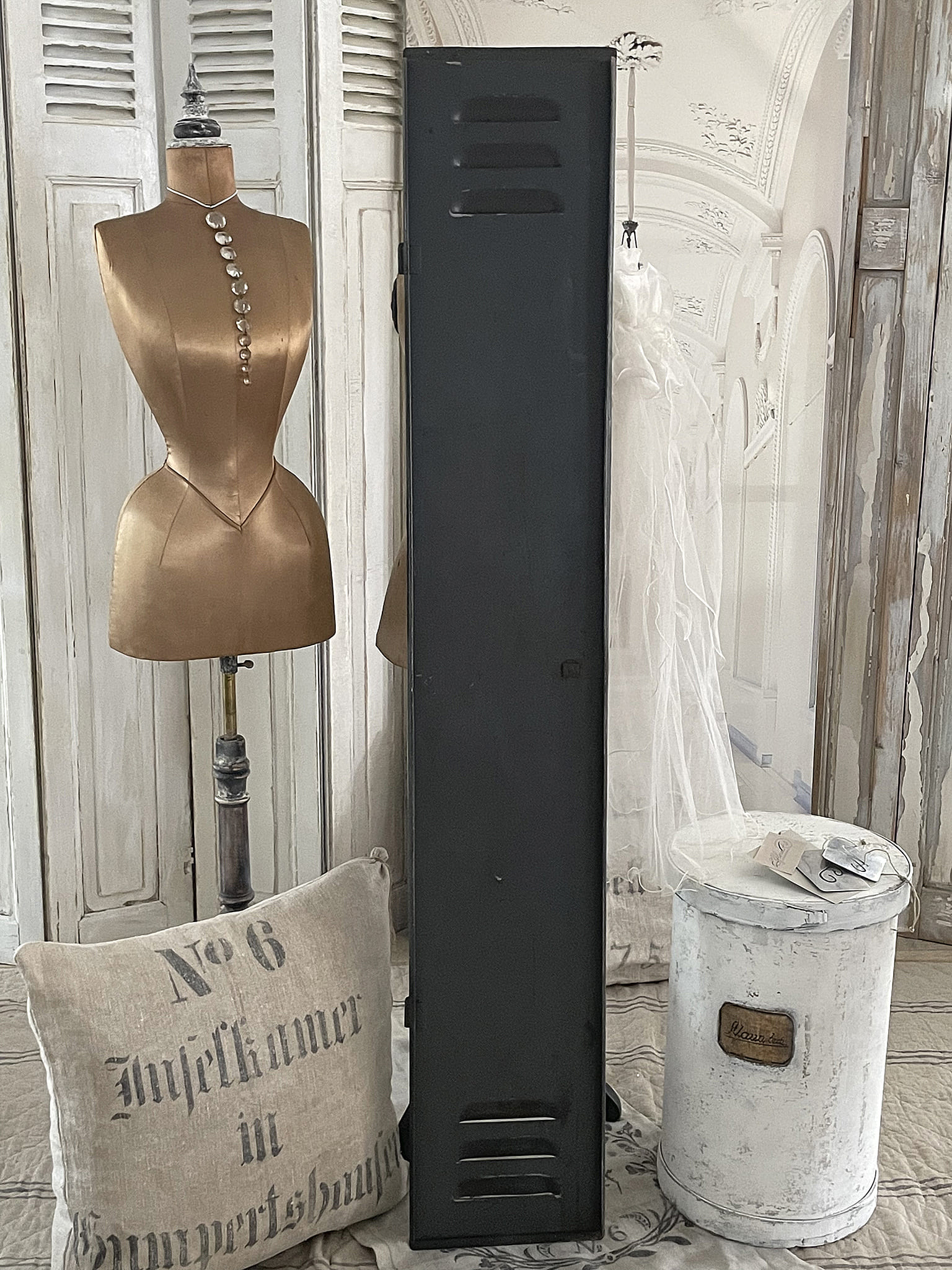 Stilvolle Deko für den Wohnraum mit Locker, Kleiderpuppe und Kissen Dekorative Elemente in einem stilvollen Wohnraum: ein schwarzer Locker, eine goldene Kleiderpuppe und ein bedrucktes Kissen.