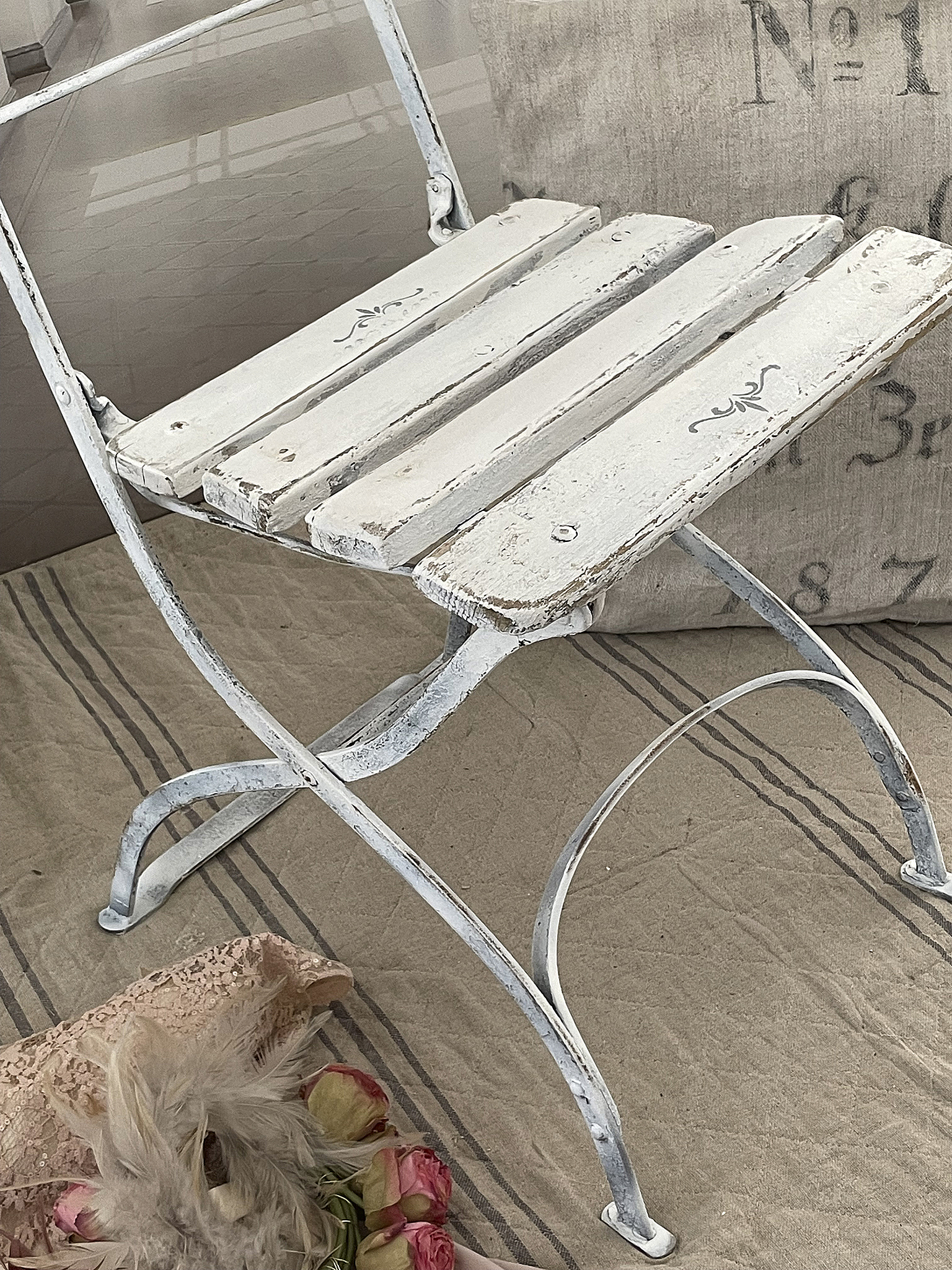 Weißer Klappstuhl aus Metall mit Holzlatten und floralen Verzierungen