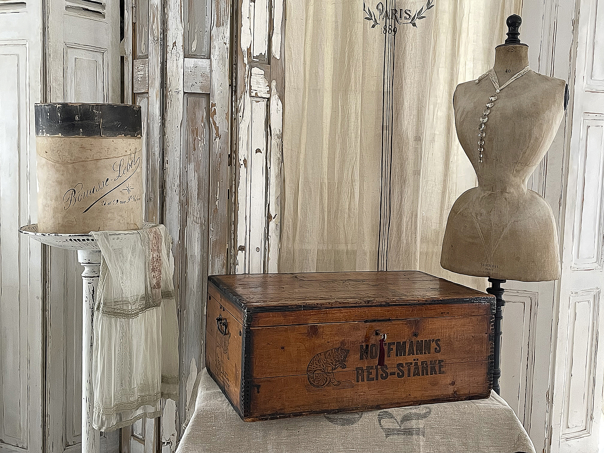 Antiker Koffer mit nostalgischem Design und Schneiderpuppe Holzkiste mit dem Aufdruck "Kofmann's Reis-Stärke" und einer eleganten Schneiderpuppe