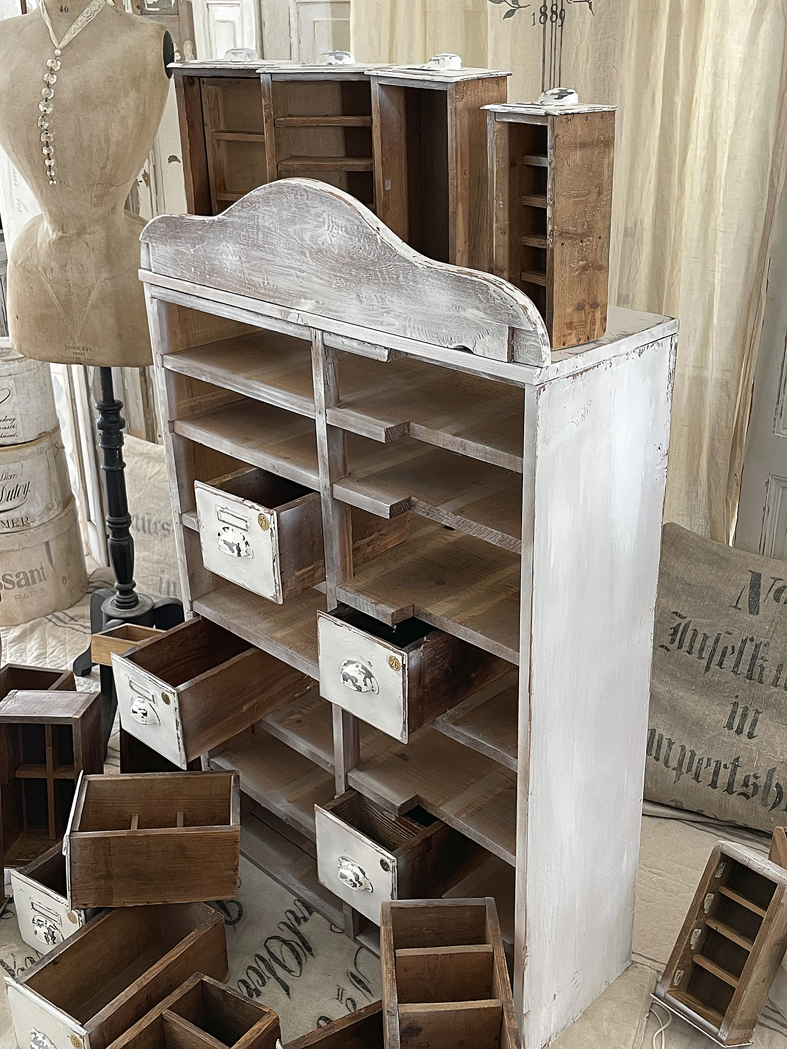 Ein dekorativer Aufbewahrungsschrank aus Holz mit mehreren offenen und geschlossenen Schubladen, umgeben von einzelnen Schubladeneinsätzen.