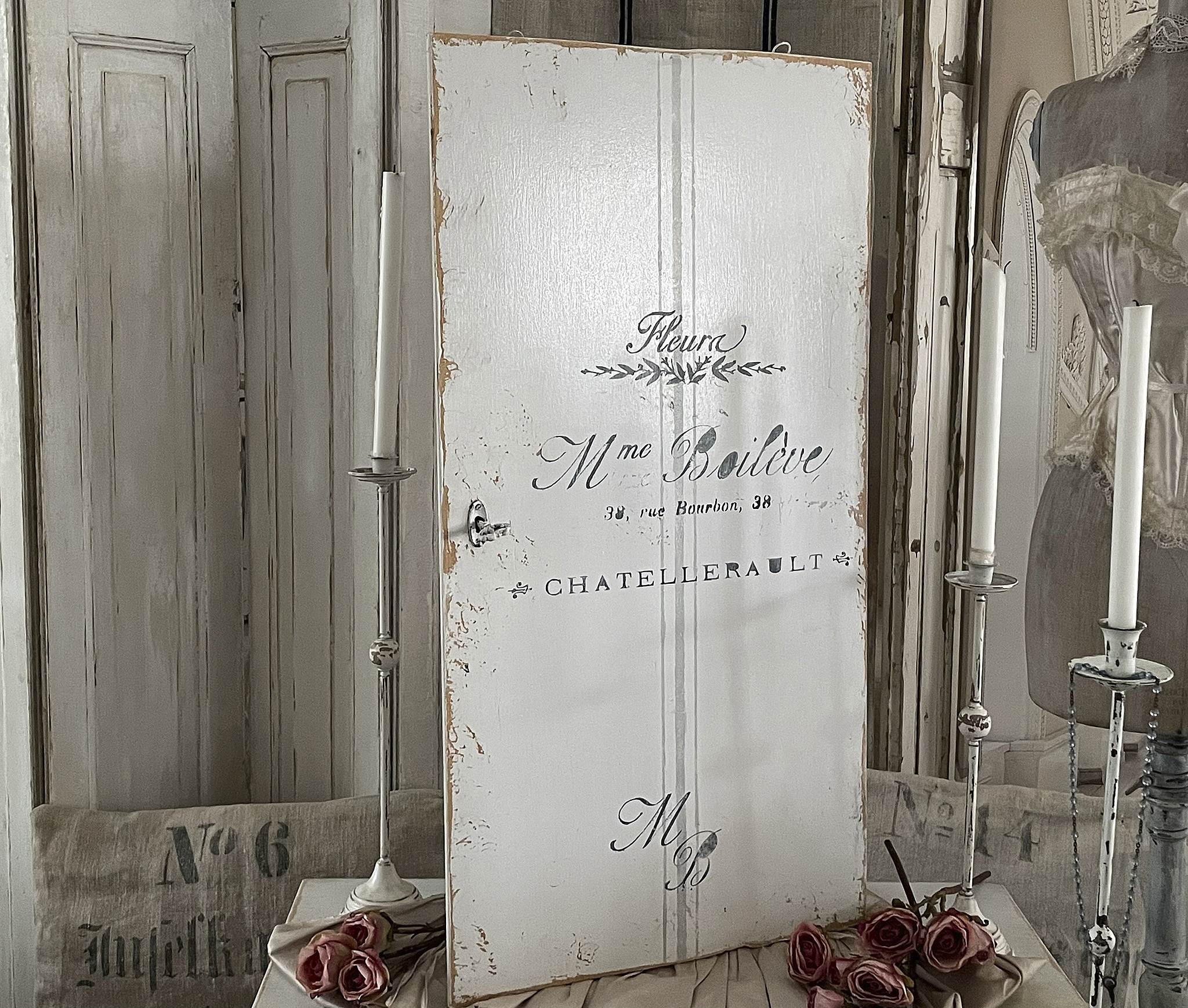 Weißes Holzschild mit Schriftzug und floralen Motiven, ideal für Vintage-Dekoration