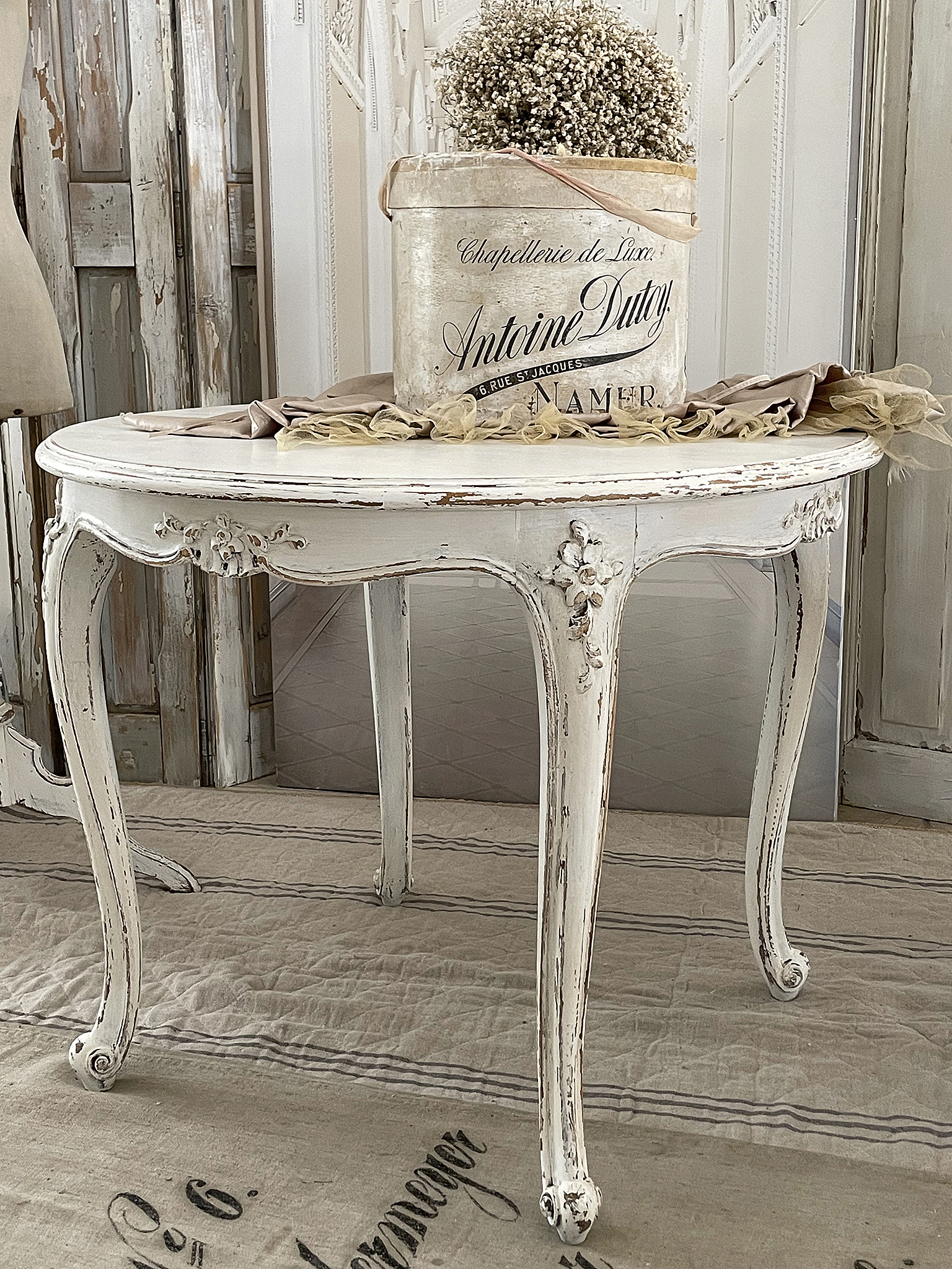 Eleganter Shabby-Chic Tisch mit vintage Deko Schöner Shabby-Chic Tisch mit einem rustikalen Eimer und Trockenblumen darauf