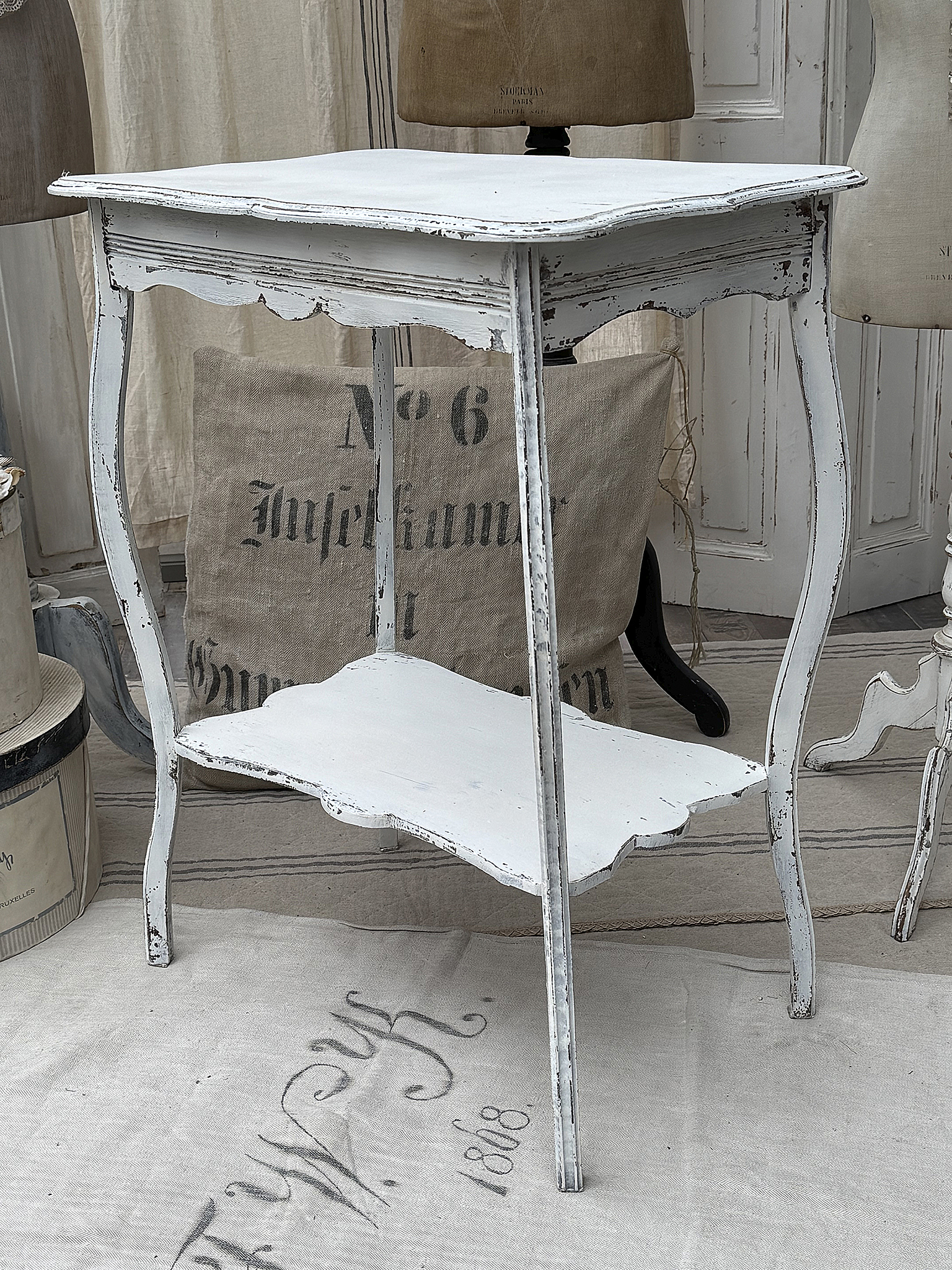 Eleganter, vintage Tisch in Weiß mit einem shabby-chic Design Antiker weißer Tisch mit geschwungenen Beinen und unterer Ablagefläche