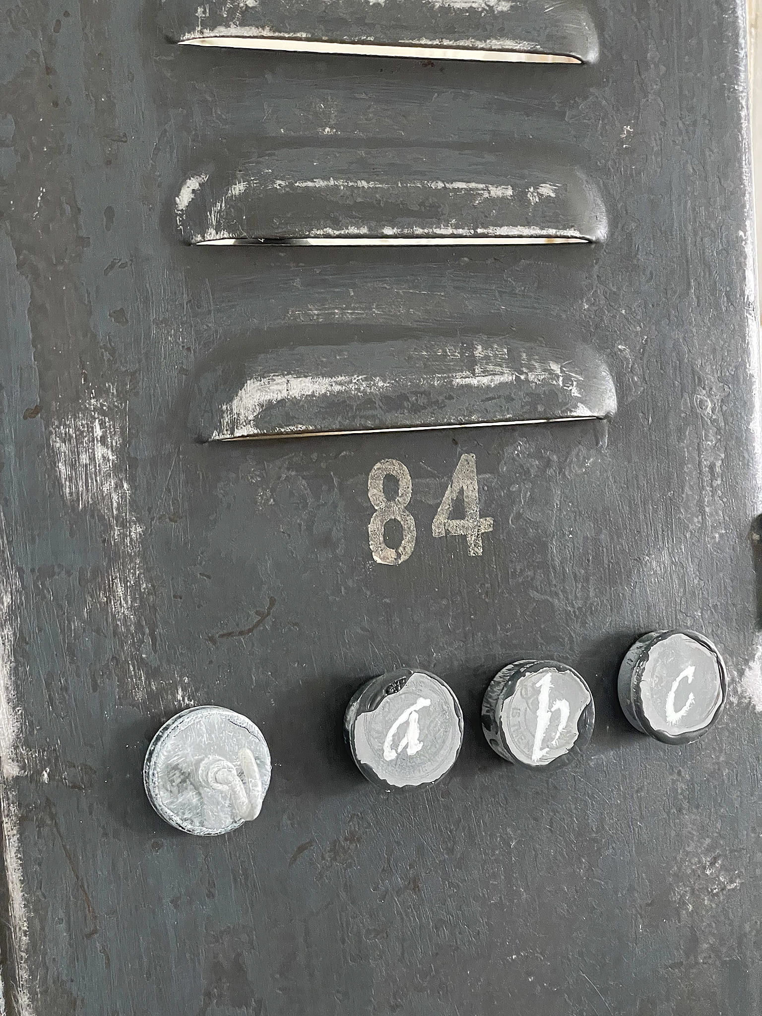 Tür mit Nummer 84 und Buchstaben a, b, c Nahaufnahme einer Tür mit der Nummer 84 und drei Buchstabenknöpfen a, b, c