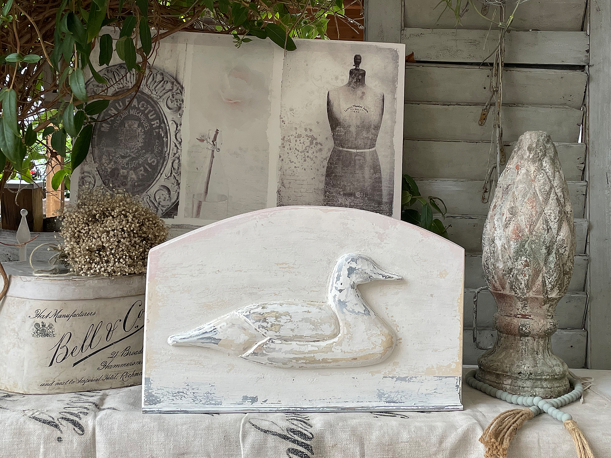 Skulptur einer Ente auf einem rustikalen Tisch mit Dekoration Rustikale Ente als Holzskulptur vor einer dekorativen Kulisse