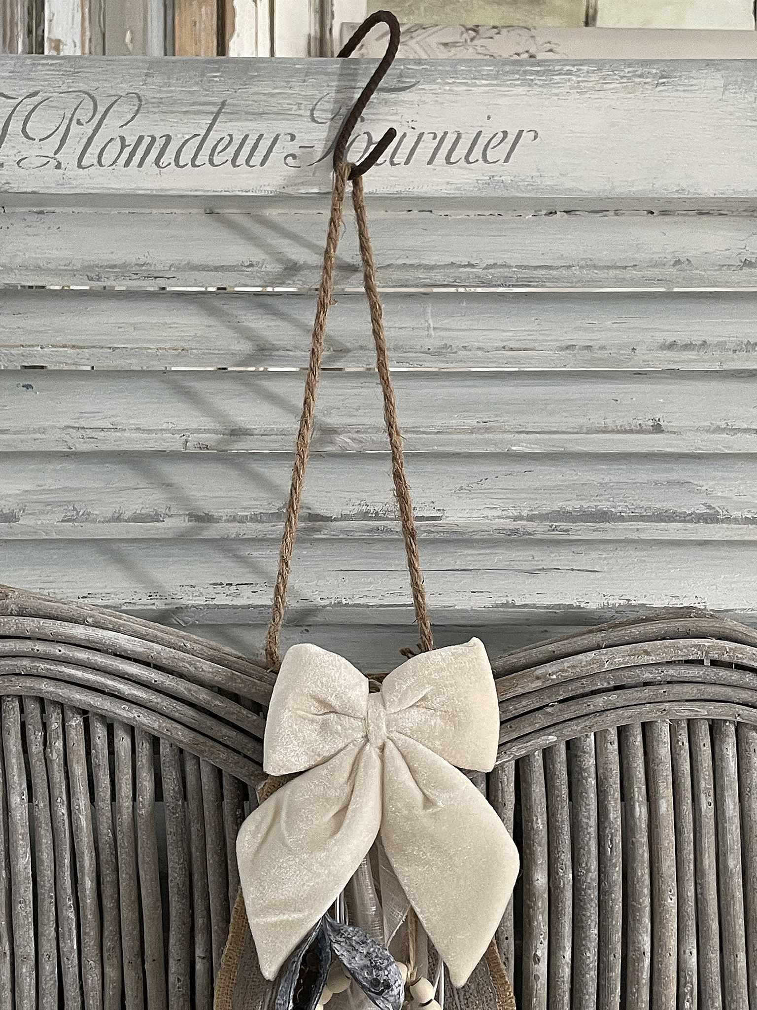 Elegante Wanddekoration mit beiger Schleife und rustikalen Akzenten Dekorative Wanddeko mit einer großen, beigen Schleife und natürlichen Elementen, an einem Holzpaneel hängend.