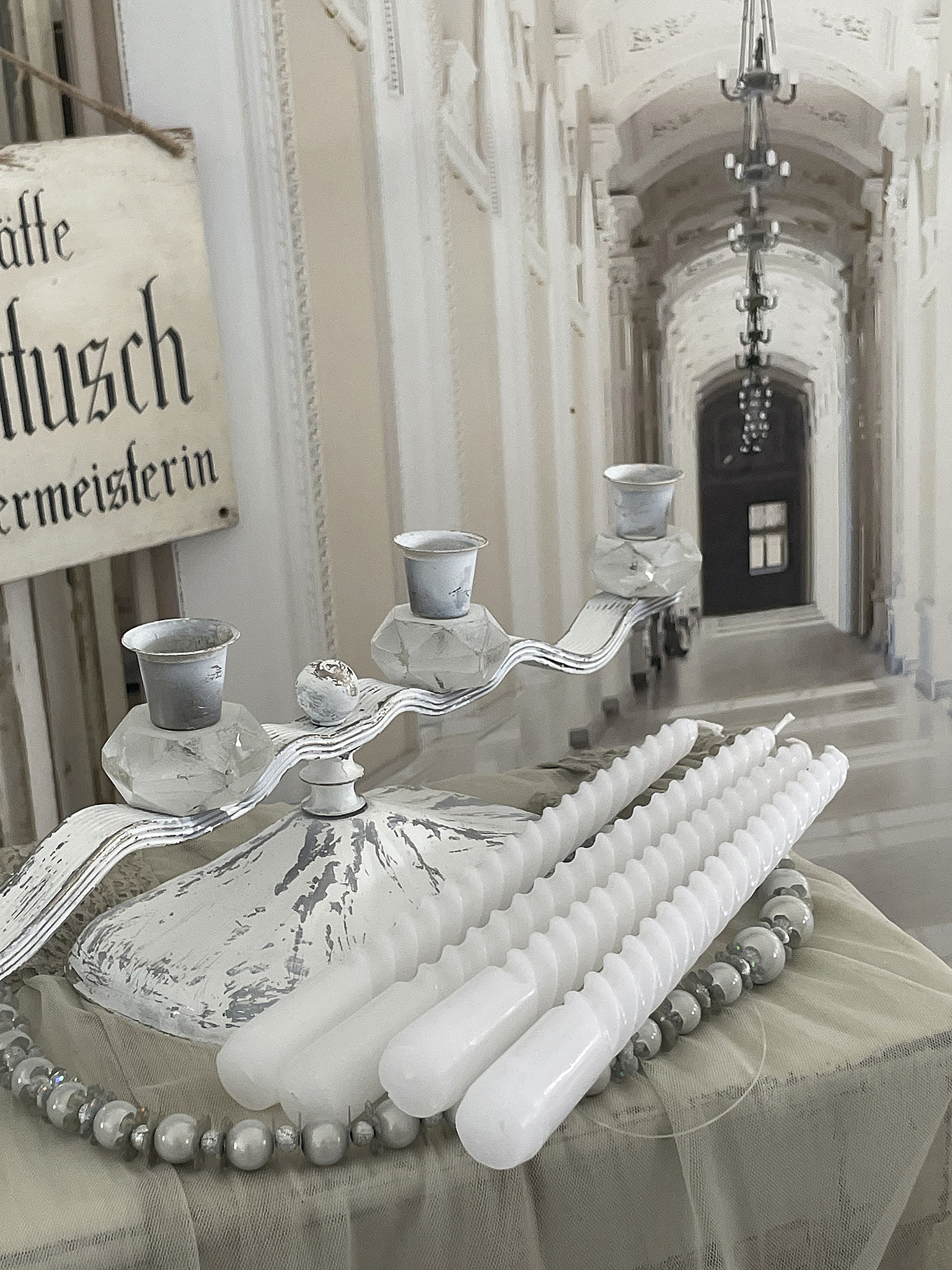 Eleganter Kerzenhalter mit weißen Kerzen für stilvolle Dekoration Dekorativer Kerzenhalter mit weißen Kerzen und Perlenkette auf einem Tisch
