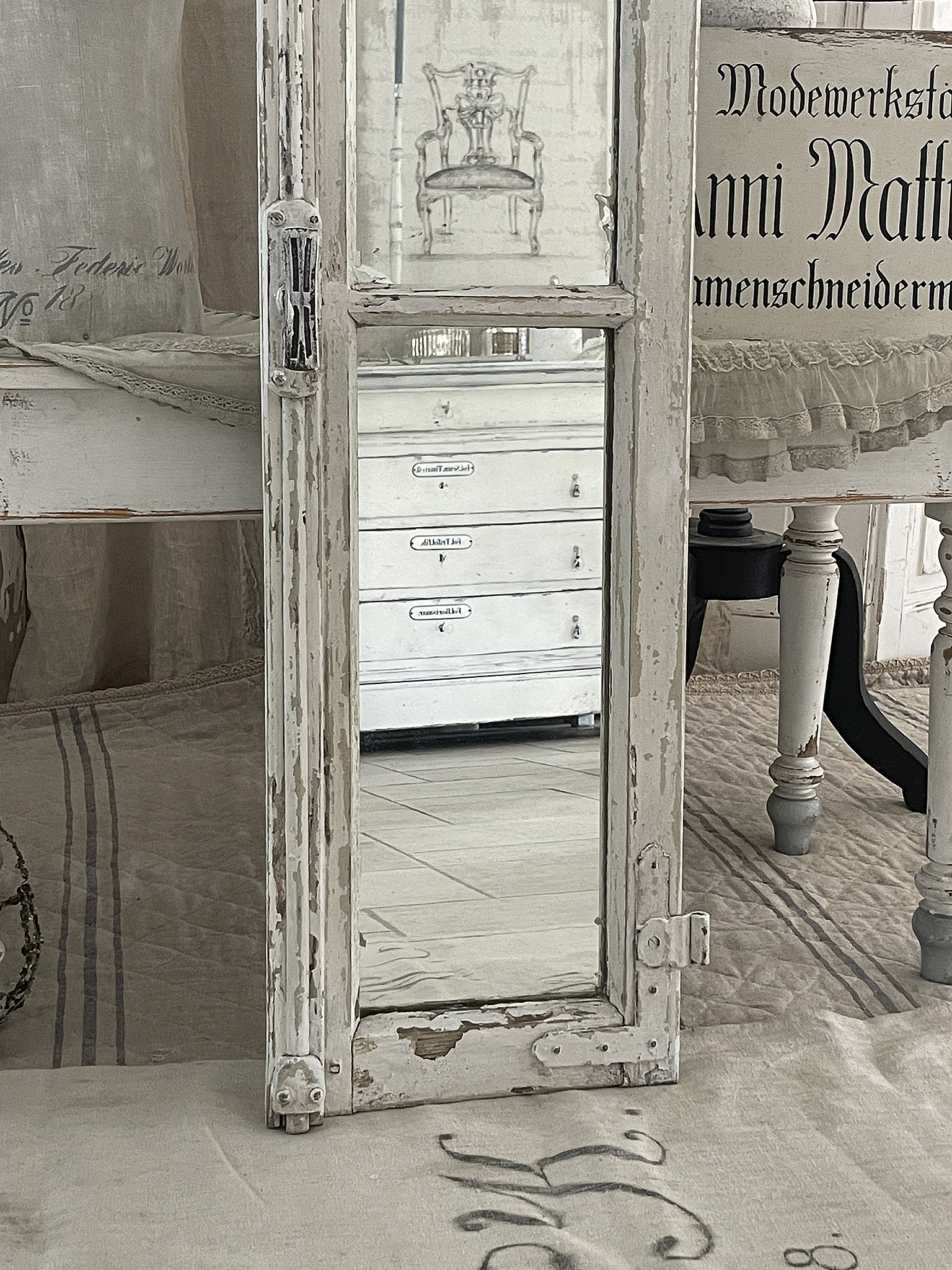 Antiker Spiegel mit shabby-chic Rahmen in weiß Antiker Spiegel im shabby-chic Stil, umgeben von weißem Holz und vintage Möbeln